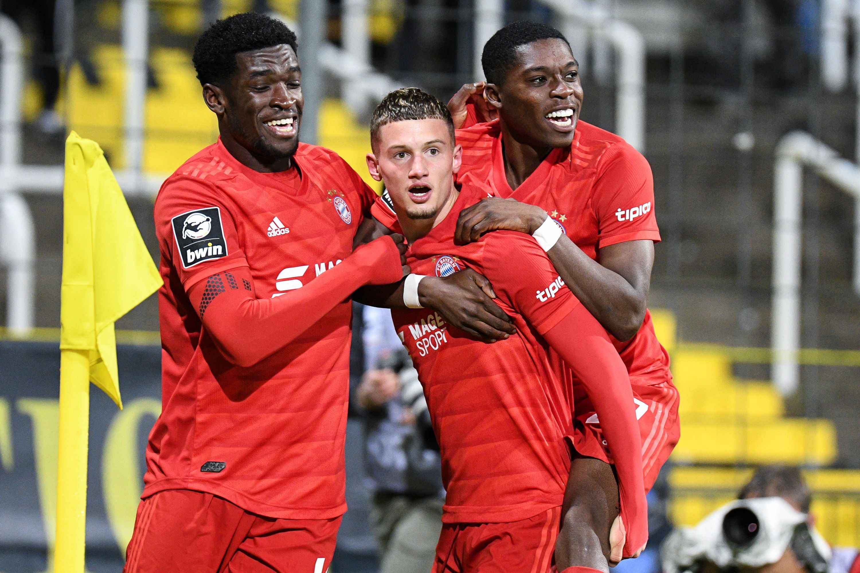 Kwasi Wriedt, Michael Cuisance und Derrick Köhn (v.l.n.r) bejubeln im Trikot von FC Bayern München einen Treffer. Aufgenommen wurd das Foto am 29. November 2019 beim Spiel von Bayern II gegen Carl-Zeiss Jena. Köhn springt Cuisance bei dem Torjubel auf den Rücken.