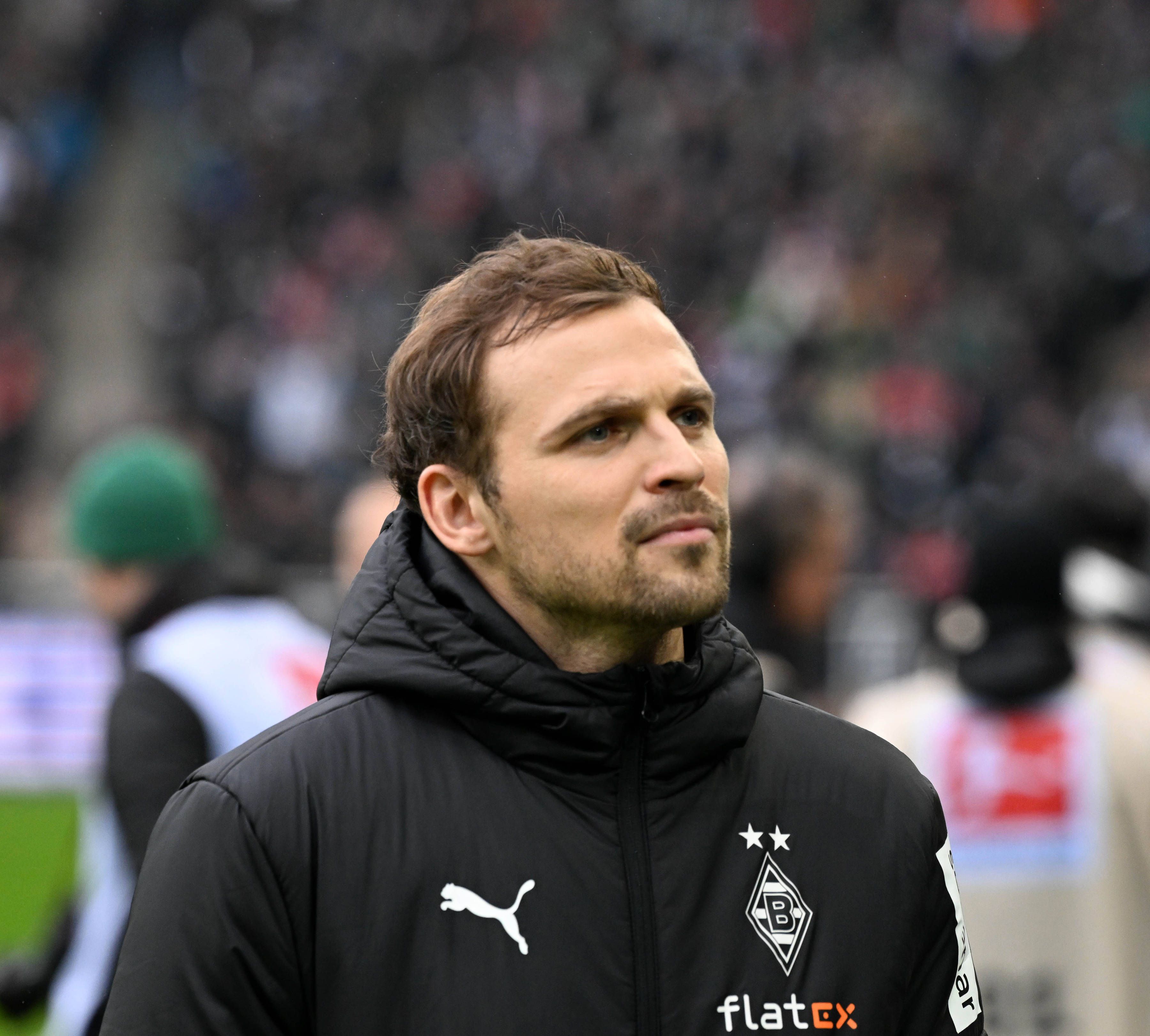 Tony Jantschke steht vor dem Bundesliga-Spiel von Borussia Mönchengladbach gegen Bayern München am 18. Februar 2023 am Spielfeldrand im Borussia-Park. Jantschke trägt eine schwarze Winterjacke von Borussia.