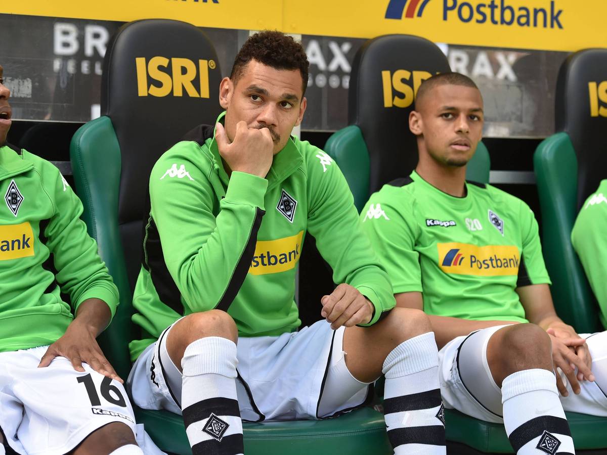 Timothee Kolodziejczak (M.) sitzt am 6. Mai 2017 auf der Ersatzbank von Borussia Mönchengladbach im Borussia-Park zwischen seinen damaligen Teamkollegen Ibrahima Traoré (l.) und Djibril Sow. Alle tragen ein grünes Trainings-Oberteil sowie weiße Hosen und Stutzen.