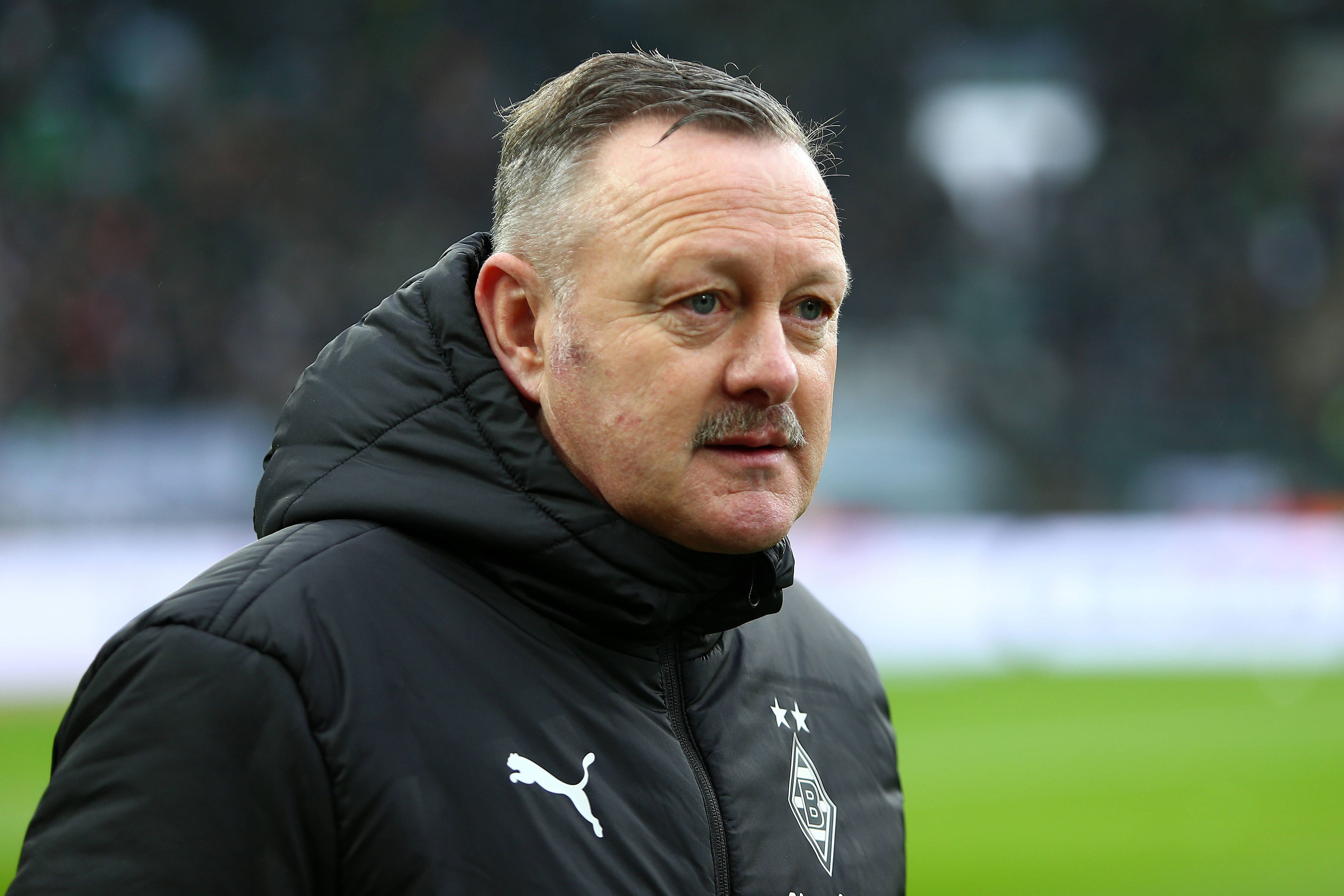 Sportdirektor Roland Virkus von Borussia Mönchengladbach vor dem Bundesliga-Spiel gegen den FC Bayern München am 18. Februar 2023. Virkus trägt eine schwarze Winterjacke mit dem Logo von Borussia Mönchengladbach und Puma.