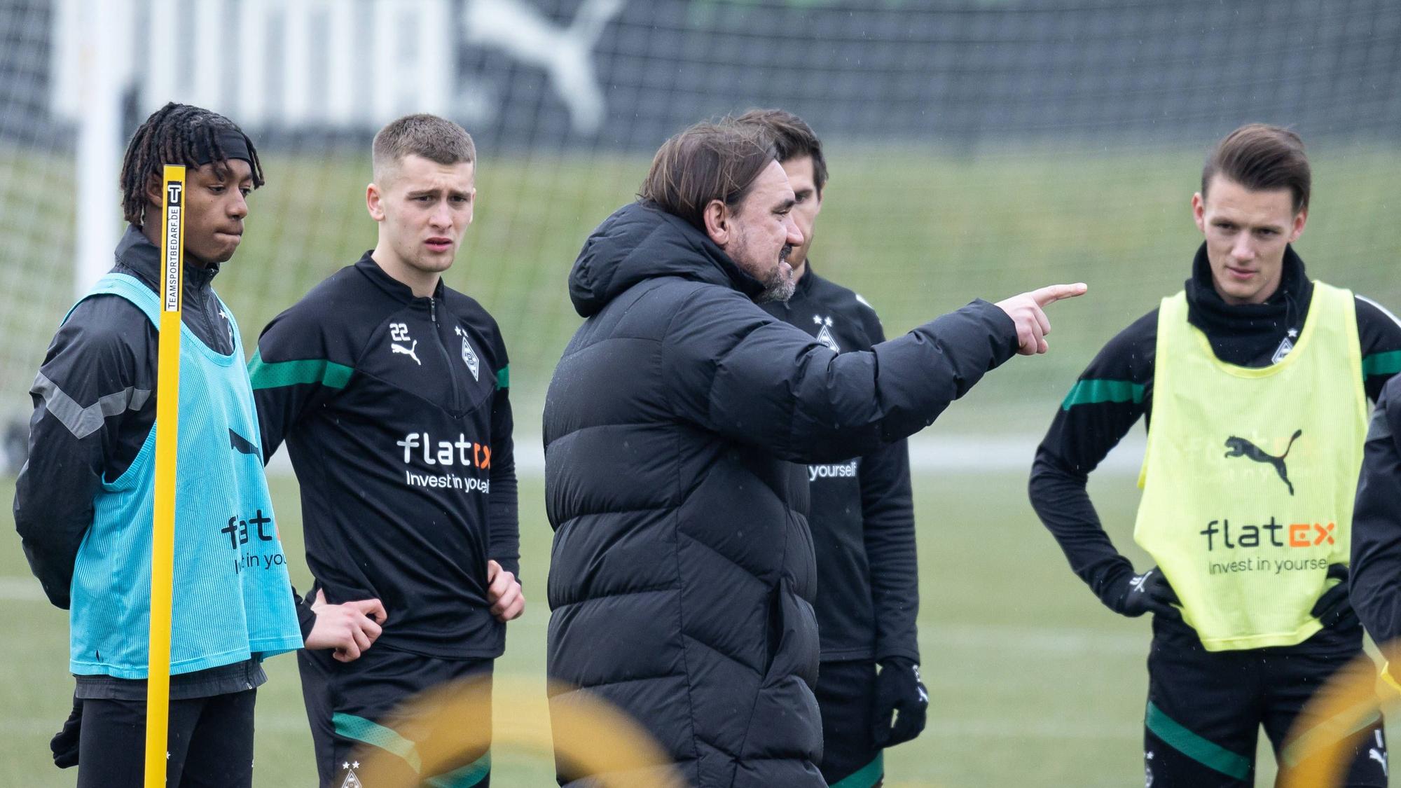 Trainer Daniel Farke gibt den Spielern von Borussia im Training Anweisungen, hier am 16. Februar 2023. Yvandro Borges Sanches, Oscar Fraulo, Jonas Hofmann und Hannes Wolf (v. l. n. r.) hören und sehen zu, während Farke mit seinem Finger etwas anzeigt.