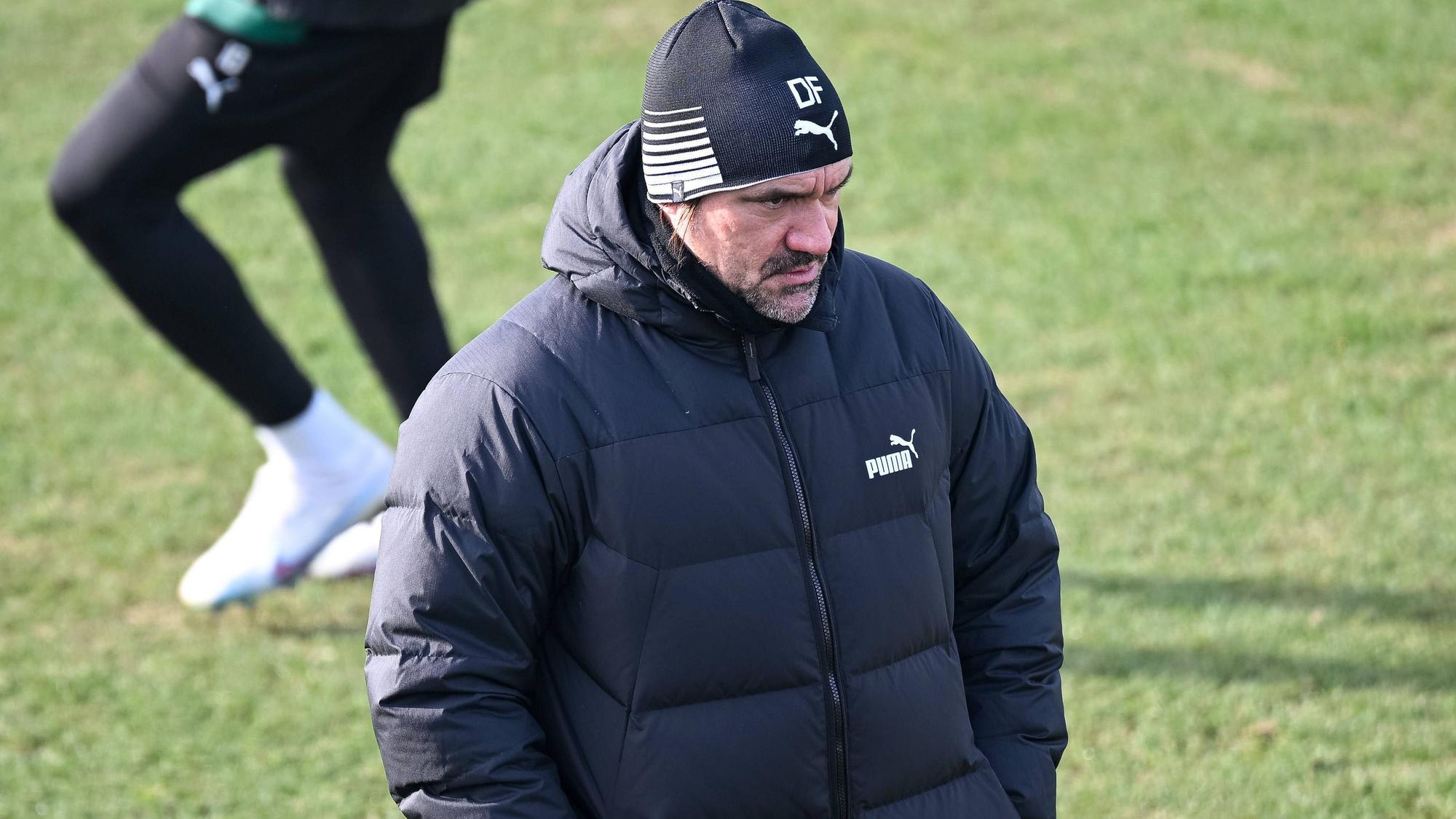 Daniel Farke, Trainer von Borussia Mönchengladbach, hier bei einer Trainingseinheit der Fohlen am 9. Februar 2023. Der Coach ist ganz in Schwarz gekleidet, trägt eine Mütze und schaut grimmig in die Ferne.