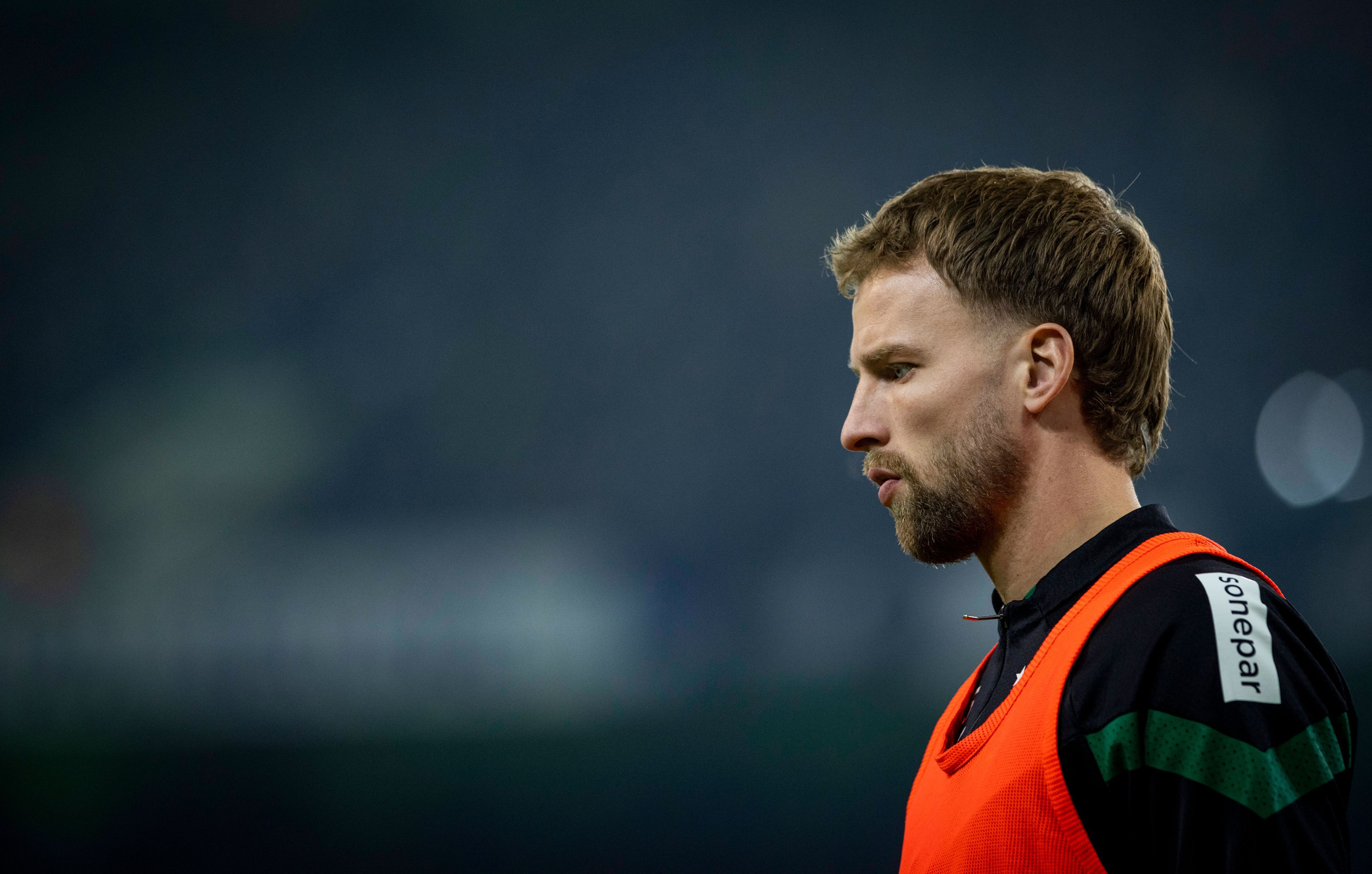Marvin Friedrich von Borussia Mönchengladbach, hier am 4. Februar 2023 beim Spiel gegen Schalke 04 an der Seitenlinie, kam bisher nur eine Minute für die Fohlen zum Zug. Das Foto zeigt ihn seitlich mit leicht gesenktem Kopf und ernstem Blick im orangen Auswechsel-Leibchen.