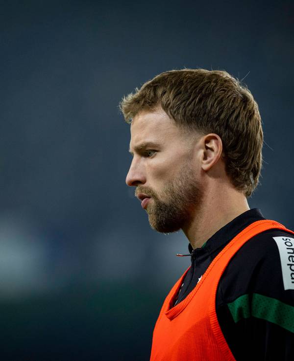 Marvin Friedrich von Borussia Mönchengladbach, hier am 4. Februar 2023 beim Spiel gegen Schalke 04 an der Seitenlinie, kam bisher nur eine Minute für die Fohlen zum Zug. Das Foto zeigt ihn seitlich mit leicht gesenktem Kopf und ernstem Blick im orangen Auswechsel-Leibchen.