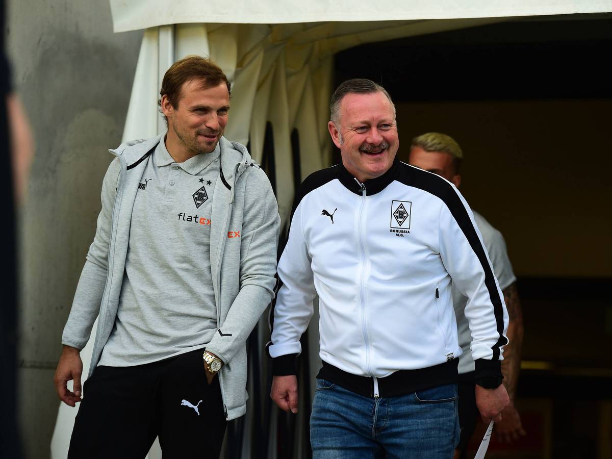 Tony Jantschke (l.) und Roland Virkus von Borussia Mönchengladbach betreten am 1. Juli 2022 den Innenraum im Stadion an der Hafenstraße vor dem Testspiel bei Rot-Weiss Essen. Beide sprechen miteinander und grinsen.