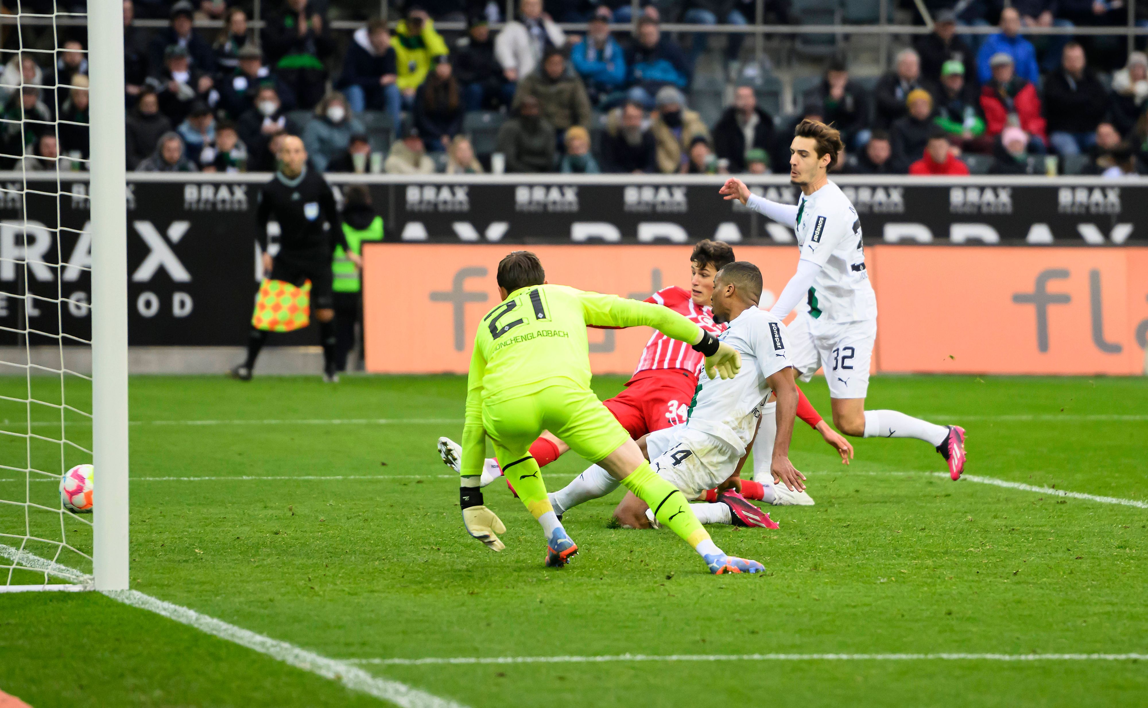 Alassane Plea grätscht den Ball im eigenen Fünfmeterraum beim Bundesliga-Spiel von Borussia Mönchengladbach gegen den SC Freiburg am 4. März 2023 ins Toraus. Hinter ihm lauert Freiburg-Spieler Merlin Röhl, der ebenfalls grätschend auf dem Rasen liegt.. Gladbach-Torhüter Tobias Sippel schaut dem Ball hinterher.