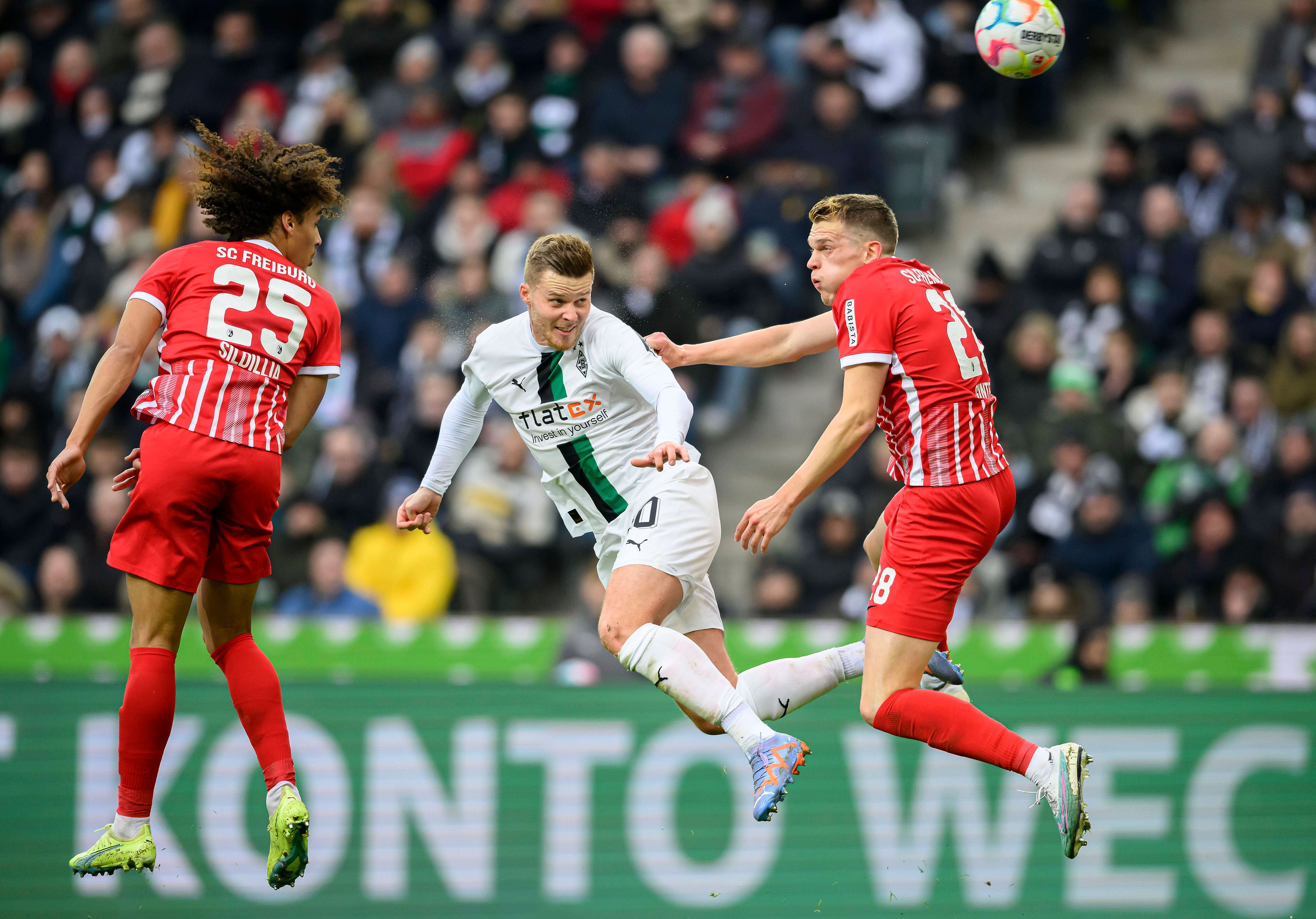 Nico Elvedi (M.) geht im Spiel von Borussia Mönchengladbach gegen den SC Freiburg am 4. März 2023 in ein Kopfball-Duell mit seinem Ex-Teamkollegen Matthias Ginter (r.) und köpft den Ball in Richtung des Freiburg-Tores. Auch Kiliann Sildillia springt dem Ball entgegen.