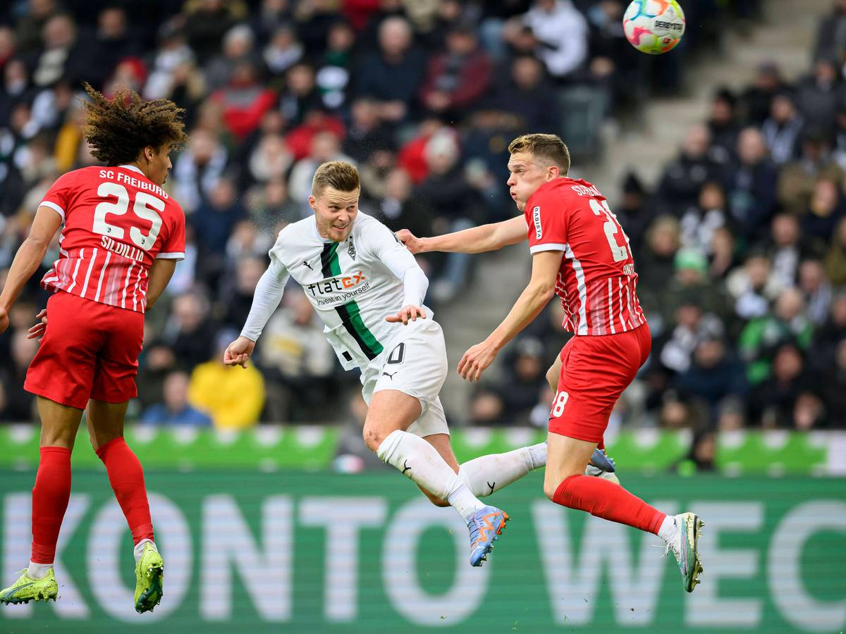 Nico Elvedi (M.) geht im Spiel von Borussia Mönchengladbach gegen den SC Freiburg am 4. März 2023 in ein Kopfball-Duell mit seinem Ex-Teamkollegen Matthias Ginter (r.) und köpft den Ball in Richtung des Freiburg-Tores. Auch Kiliann Sildillia springt dem Ball entgegen.