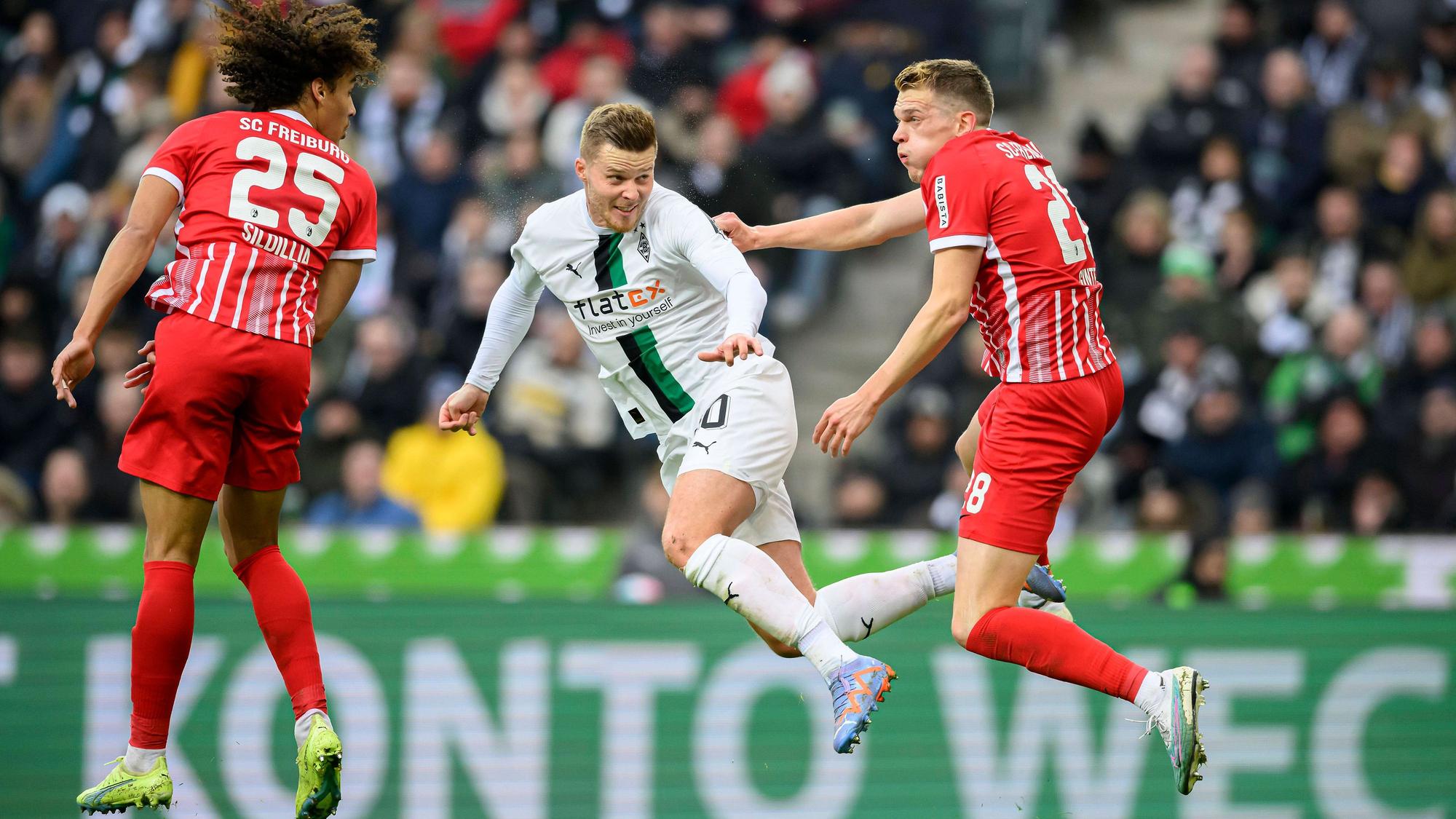 Nico Elvedi (M.) geht im Spiel von Borussia Mönchengladbach gegen den SC Freiburg am 4. März 2023 in ein Kopfball-Duell mit seinem Ex-Teamkollegen Matthias Ginter (r.) und köpft den Ball in Richtung des Freiburg-Tores. Auch Kiliann Sildillia springt dem Ball entgegen.