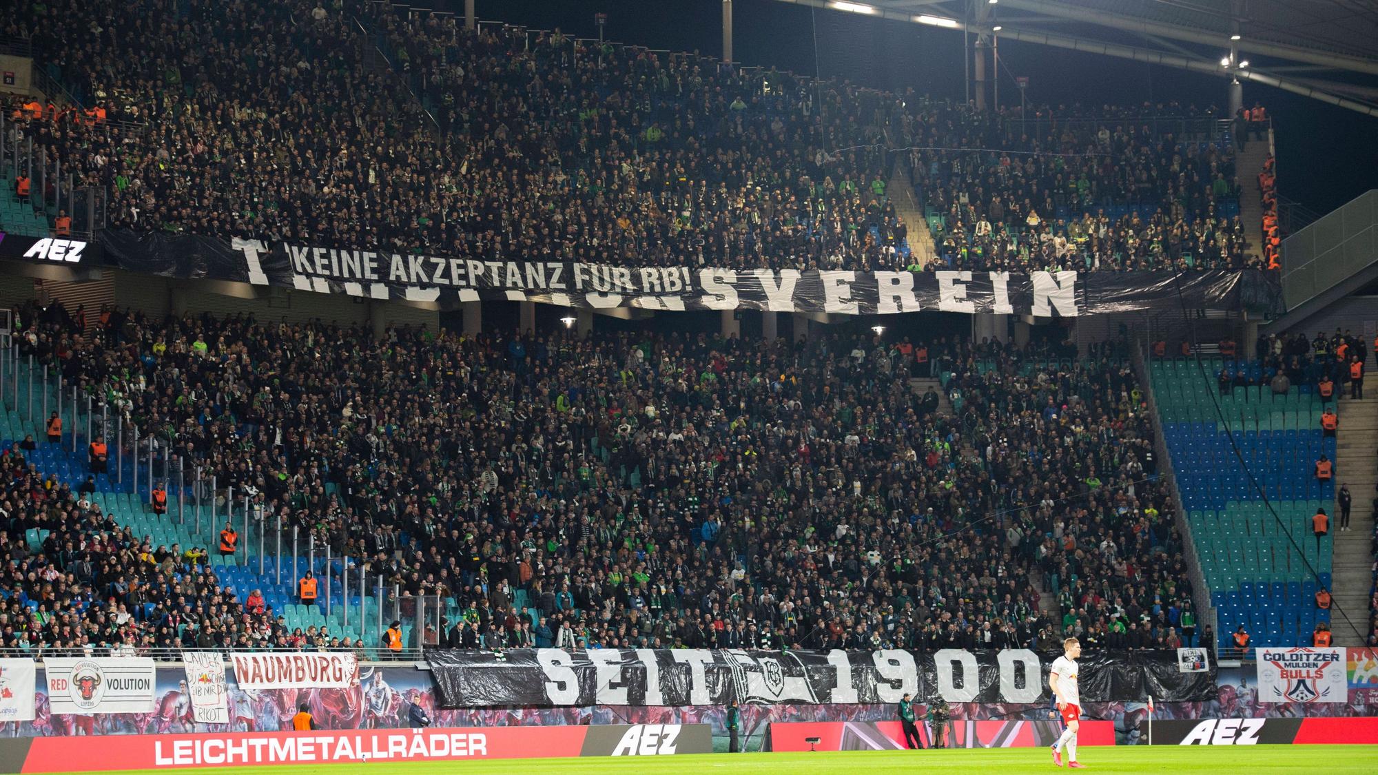 Gladbach-Fans im Gäste-Block der Leipziger Arena bringen ihren Standpunkt zu RB Leipzig zum Ausdruck. Dieses Foto stammt vom 1. Februar 2020. Zu sehen sind riesiger Banner mit Aufschriften.