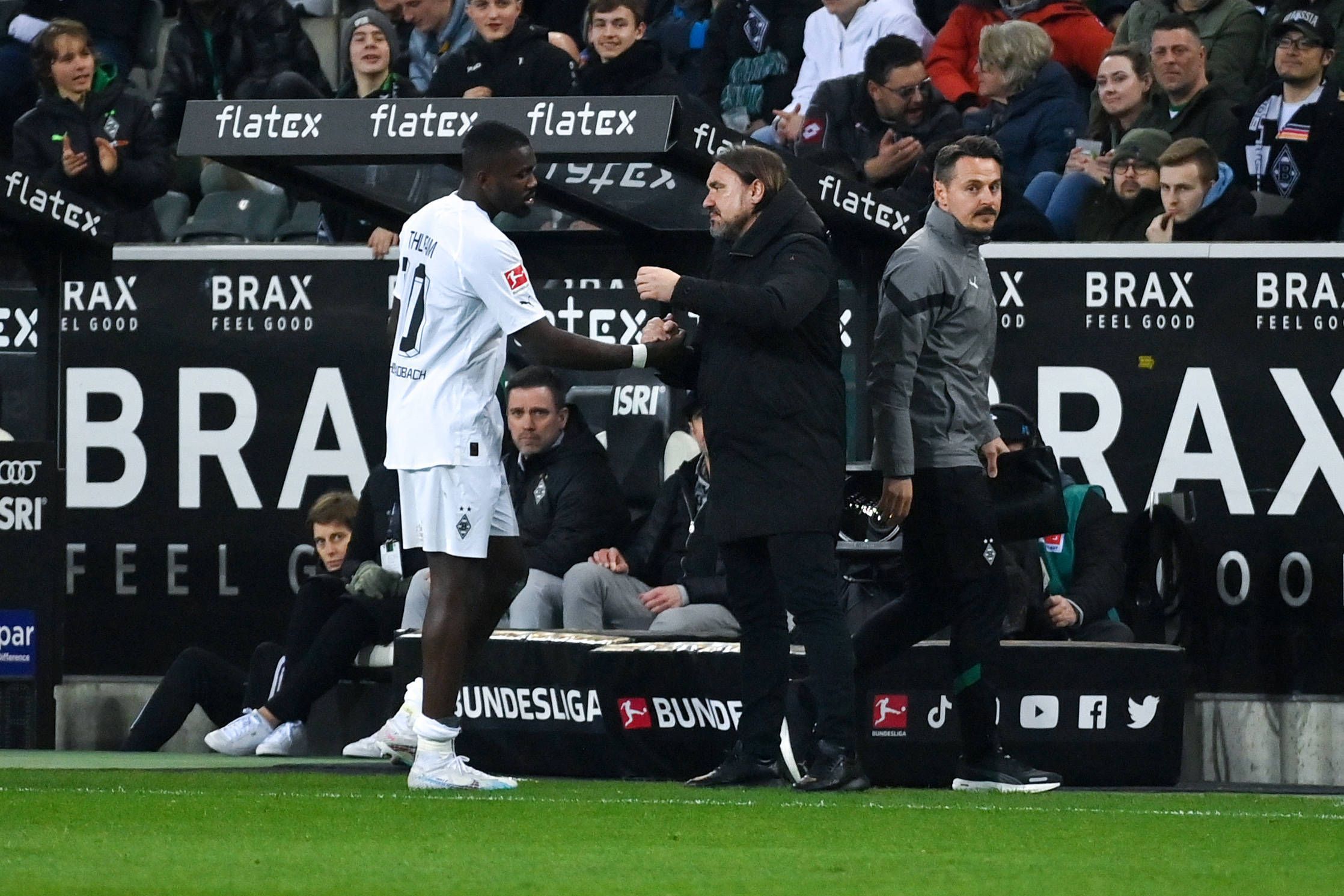 Gladbach-Trainer Daniel Farke (r.) klatscht mit seinem Stürmer Marcus Thuram nach dessen Auswechslung im Bundesliga-Spiel von Borussia Mönchengladbach gegen Werder Bremen am 17. März 2023 ab.