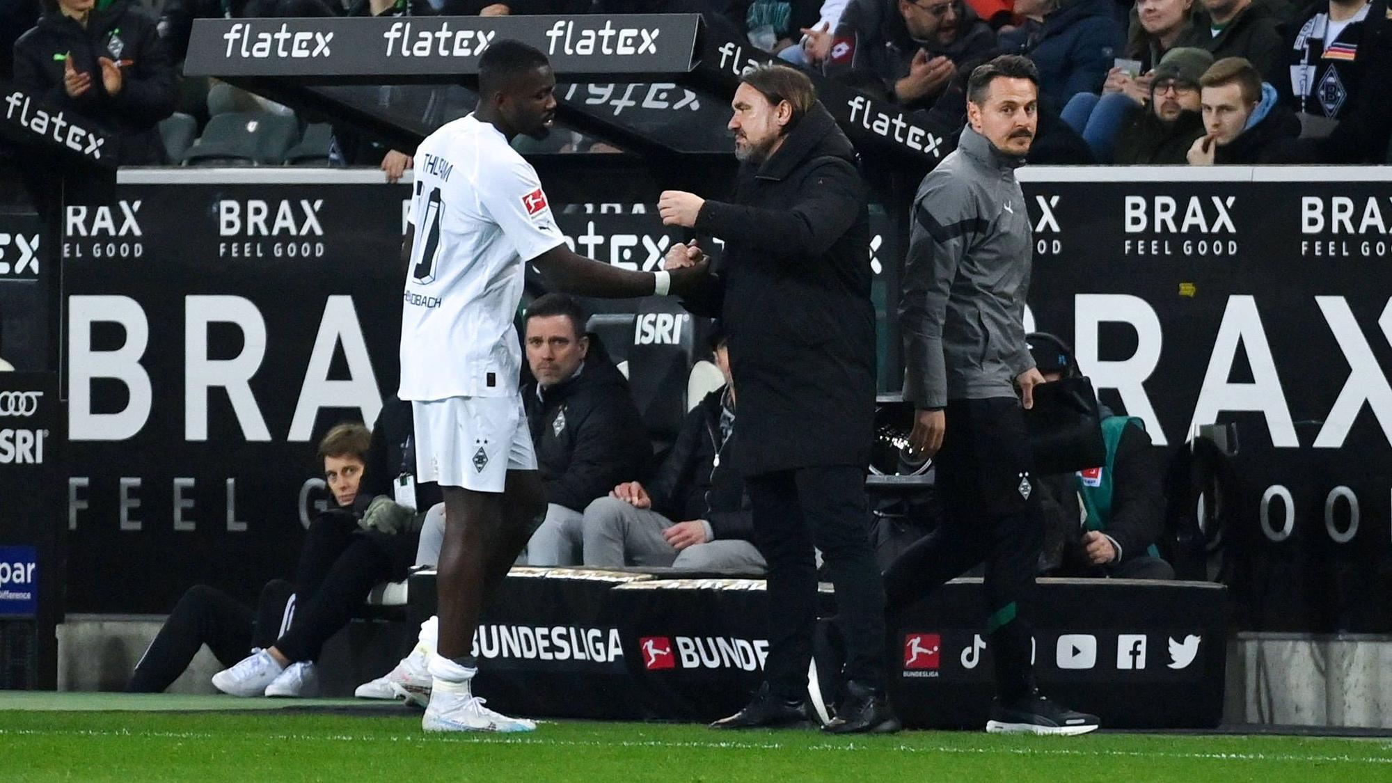 Gladbach-Trainer Daniel Farke (r.) klatscht mit seinem Stürmer Marcus Thuram nach dessen Auswechslung im Bundesliga-Spiel von Borussia Mönchengladbach gegen Werder Bremen am 17. März 2023 ab.