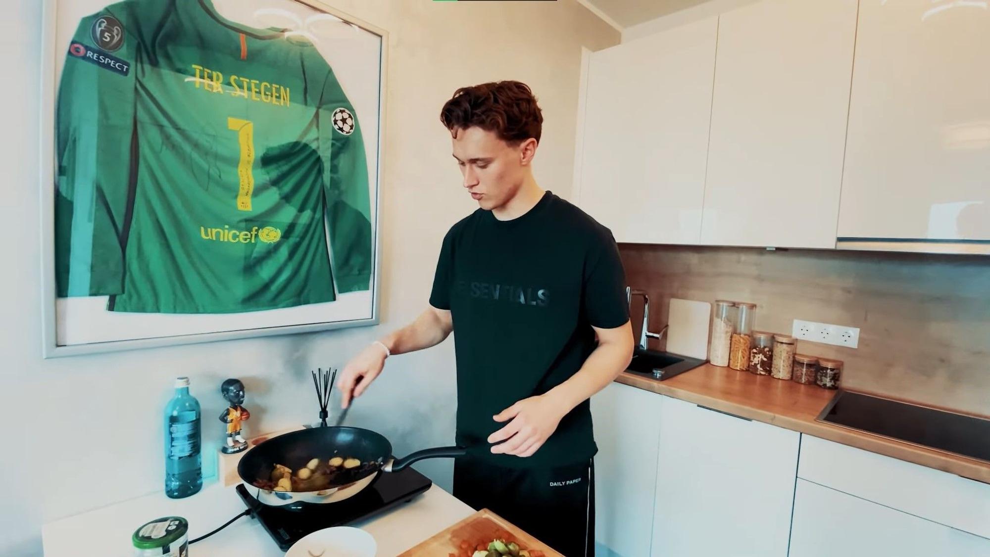 Jan Olschowsky in einem Kochvideo auf seinem YouTube-Kanal. Im Hintergrund hängt ein Trikot von Marc-André ter Stegen an der Wand der Küche.