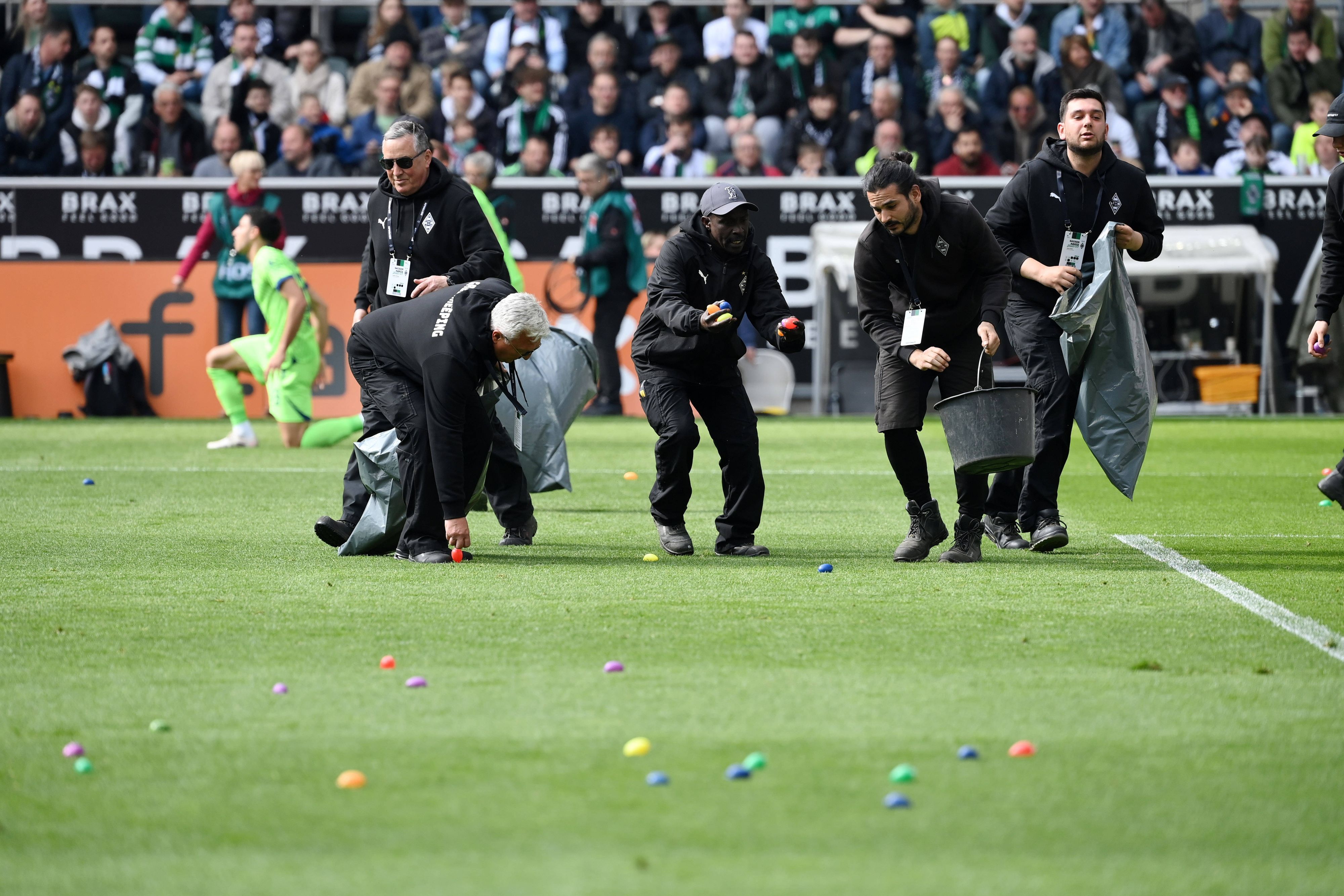 Ordner sammeln Ostereier vom Spielfeld auf, die von den Gladbach-Fans in der Nordkurve geworfen wurden.