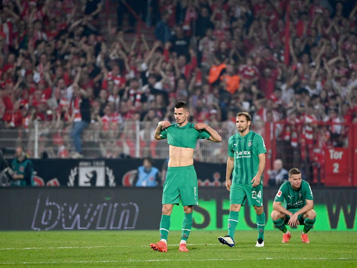 Fans von Union Berlin bejubeln den Sieg ihres Teams im Hintergrund, während Spieler von Borussia Mönchengladbach ihrer Enttäuschung auf dem Rasen im Stadion An der Alten Försterei freien Lauf lassen.