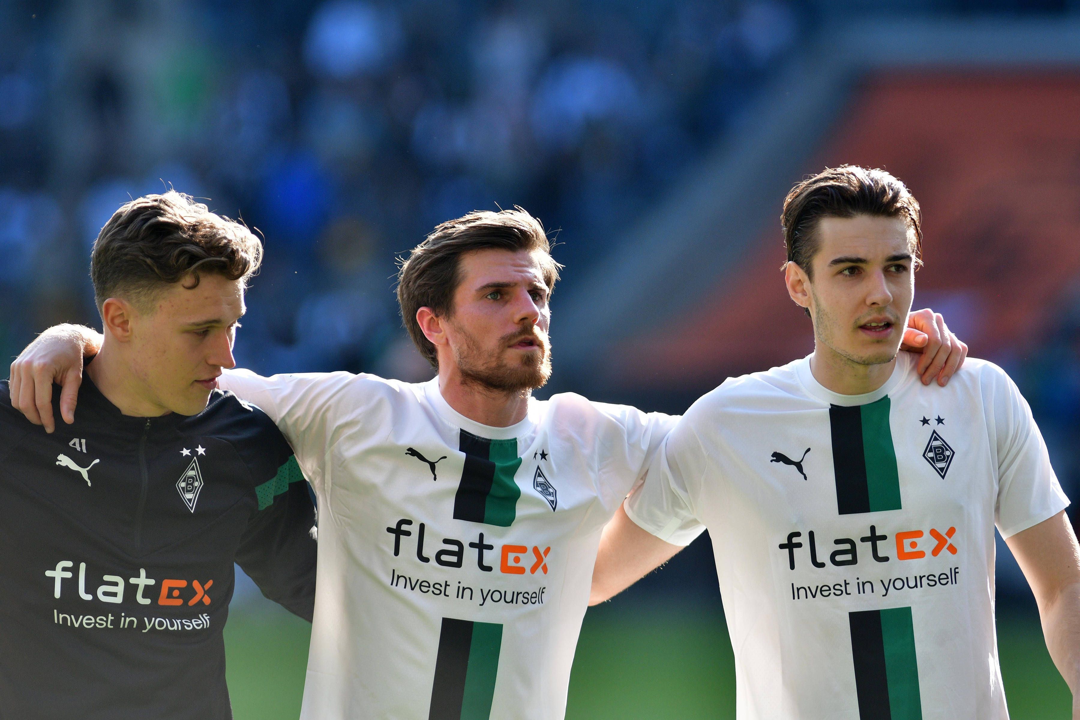 Jonas Hofmann (M.) feiert am 9. April 2023 den Sieg von Borussia Mönchengladbach gegen den VfL Wolfsburg mit Jan Olschowsky (l.) und Florian Neuhaus. Das Gladbach-Trio steht Arm in Arm vor der Nordkurve.