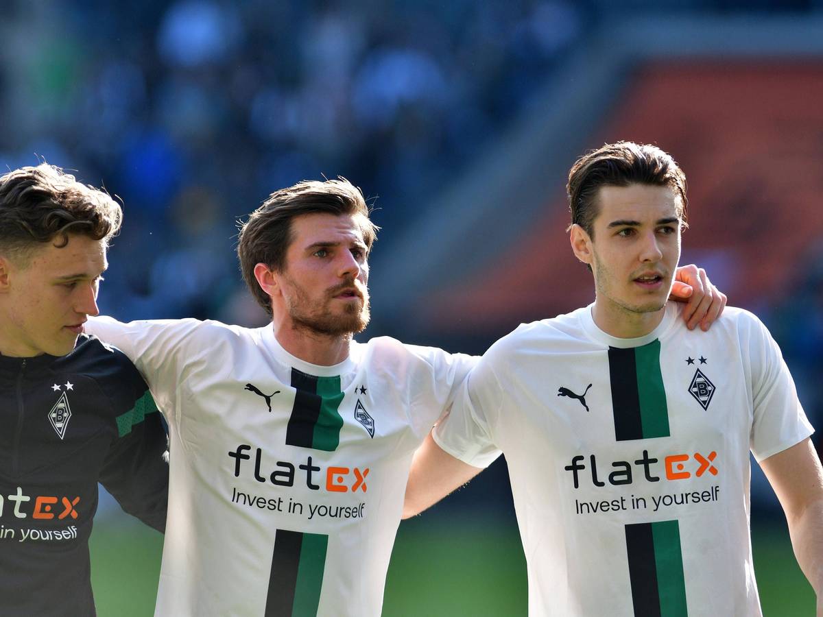 Jonas Hofmann (M.) feiert am 9. April 2023 den Sieg von Borussia Mönchengladbach gegen den VfL Wolfsburg mit Jan Olschowsky (l.) und Florian Neuhaus. Das Gladbach-Trio steht Arm in Arm vor der Nordkurve.