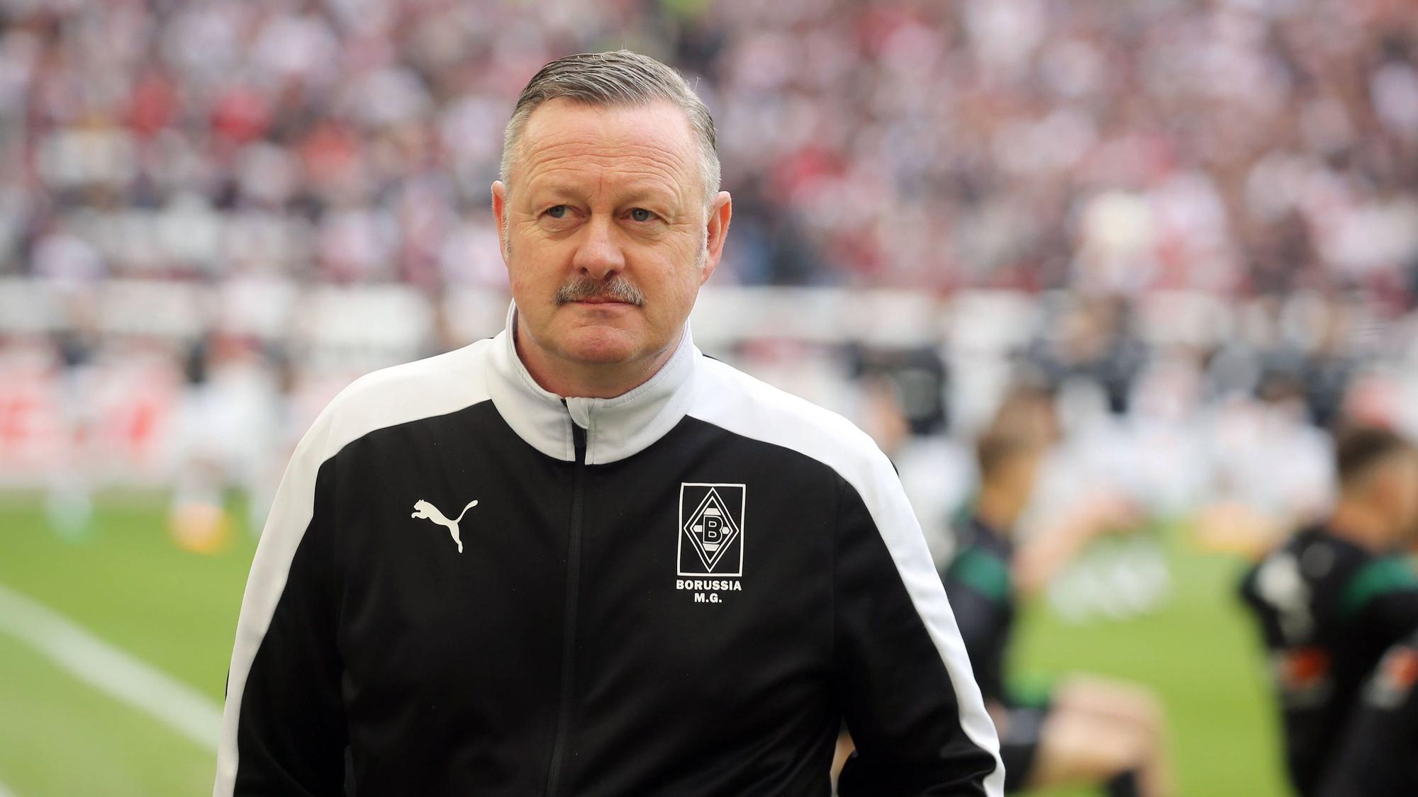 Roland Virkus ist Manager bei Fußball-Bundesligist Borussia Mönchengladbach. Hier ist der 56-Jährige am 29. April 2023 vor der Bundesligapartie beim VfB Stuttgart zu sehen. Virkus blickt in das Stadionrund, im Hintergrund wärmen sich Spieler auf.