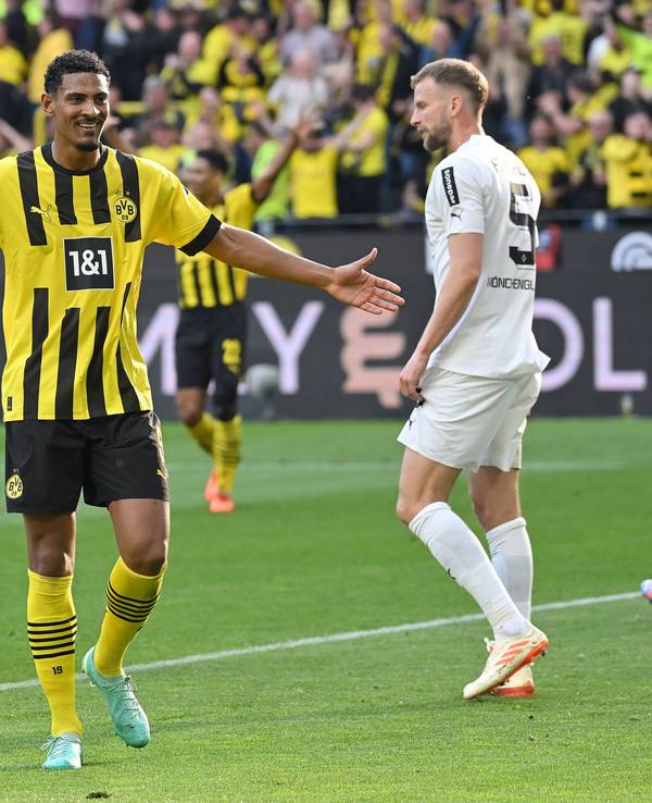 Ein Foto mit Symbolcharakter im Bundesliga-Topspiel (13. Mai 2023): Die Dortmund-Profis um Torschütze Sebastian Haller (M.) feiern eine Galavorstellung, im Hintergrund ist mit Marvin Friedrich (r.) ein enttäuschter Gladbach-Spieler zu sehen. Haller breitet die Arme aus.