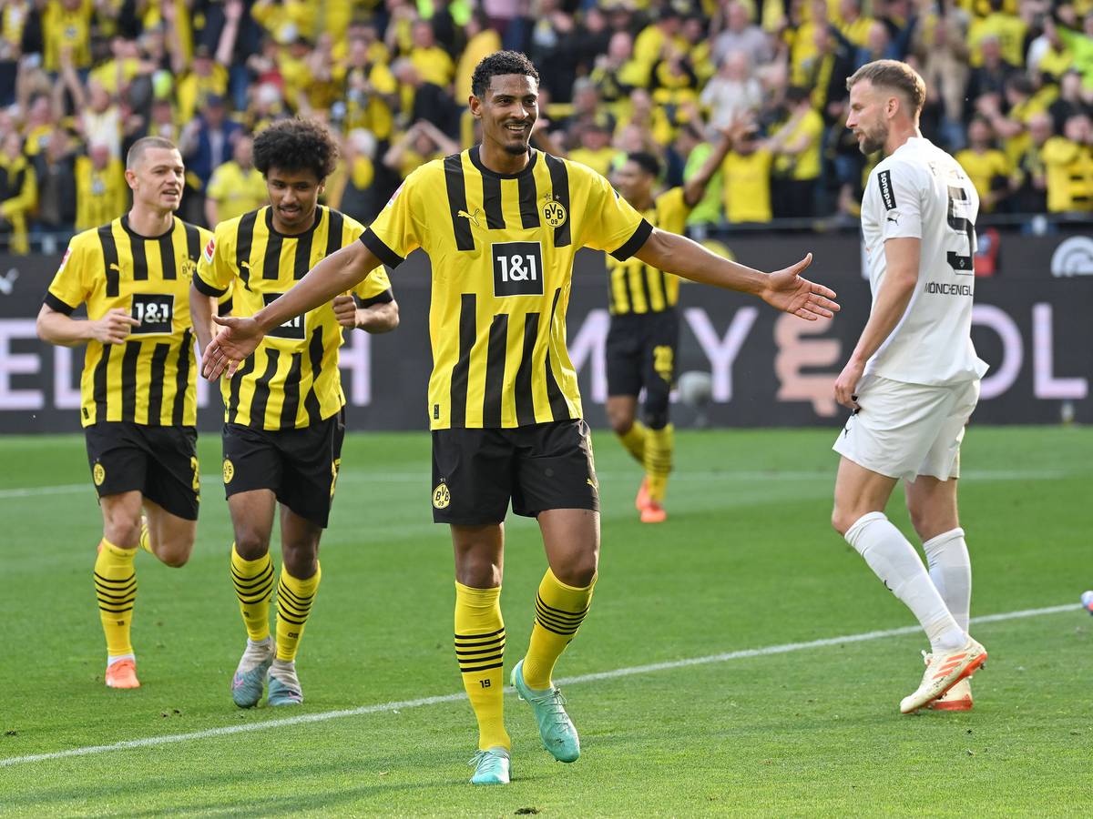 Ein Foto mit Symbolcharakter im Bundesliga-Topspiel (13. Mai 2023): Die Dortmund-Profis um Torschütze Sebastian Haller (M.) feiern eine Galavorstellung, im Hintergrund ist mit Marvin Friedrich (r.) ein enttäuschter Gladbach-Spieler zu sehen. Haller breitet die Arme aus.