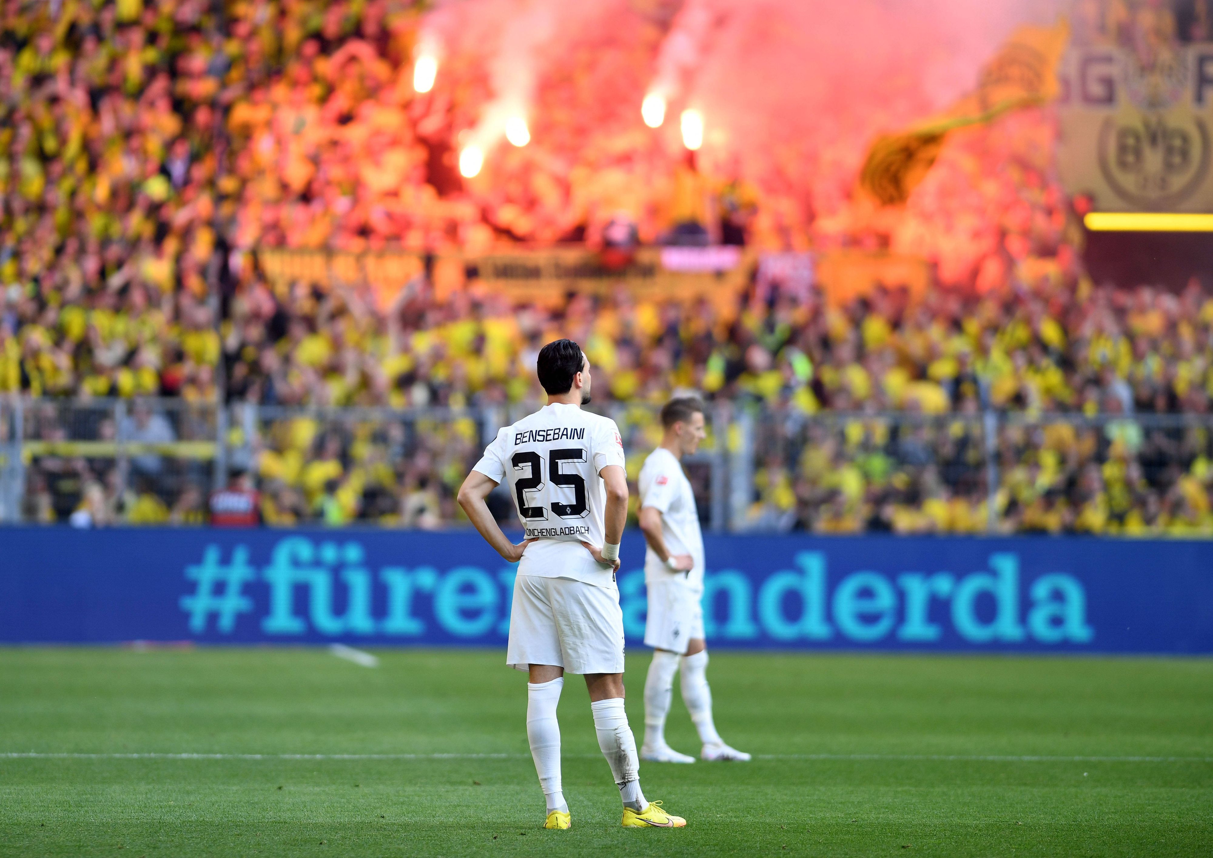 Ramy Bensebaini von Borussia Mönchengladbach ist nach einem Gegentreffer am 13. Mai 2023 bei Borussia Dortmund konsterniert. Er steht mit in die Hüften gestemmten Armen auf dem Rasen, im Hintergrund feiern die BVB-Fans auf der Südtribüne.