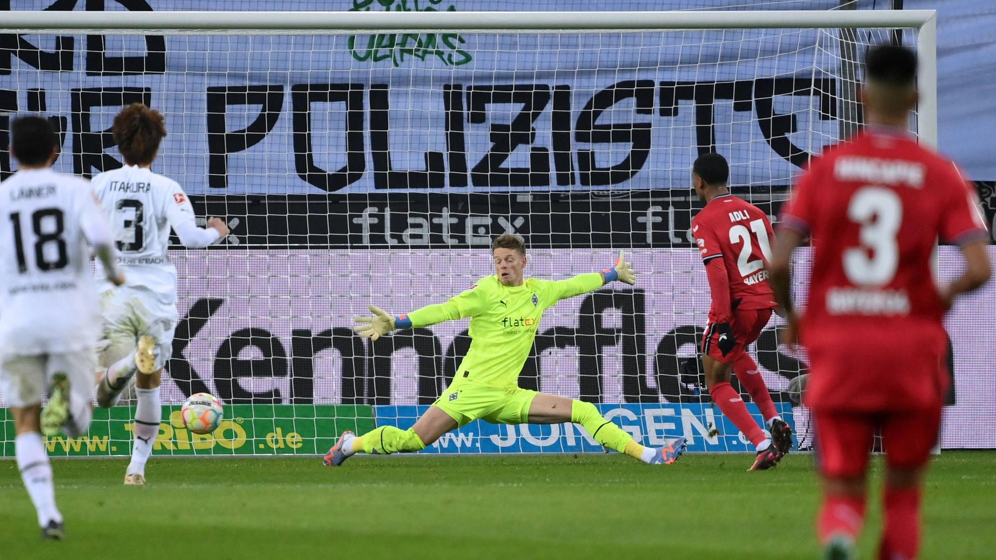 Amine Adli (Nummer 21) erzielt im Bundesliga-Spiel von Bayer Leverkusen bei Borussia Mönchengladbach am 22. Januar 2023 den Treffer zum zwischenzeitlichen 2:0. Jonas Omlin versucht vergeblich, den Ball zu parieren.