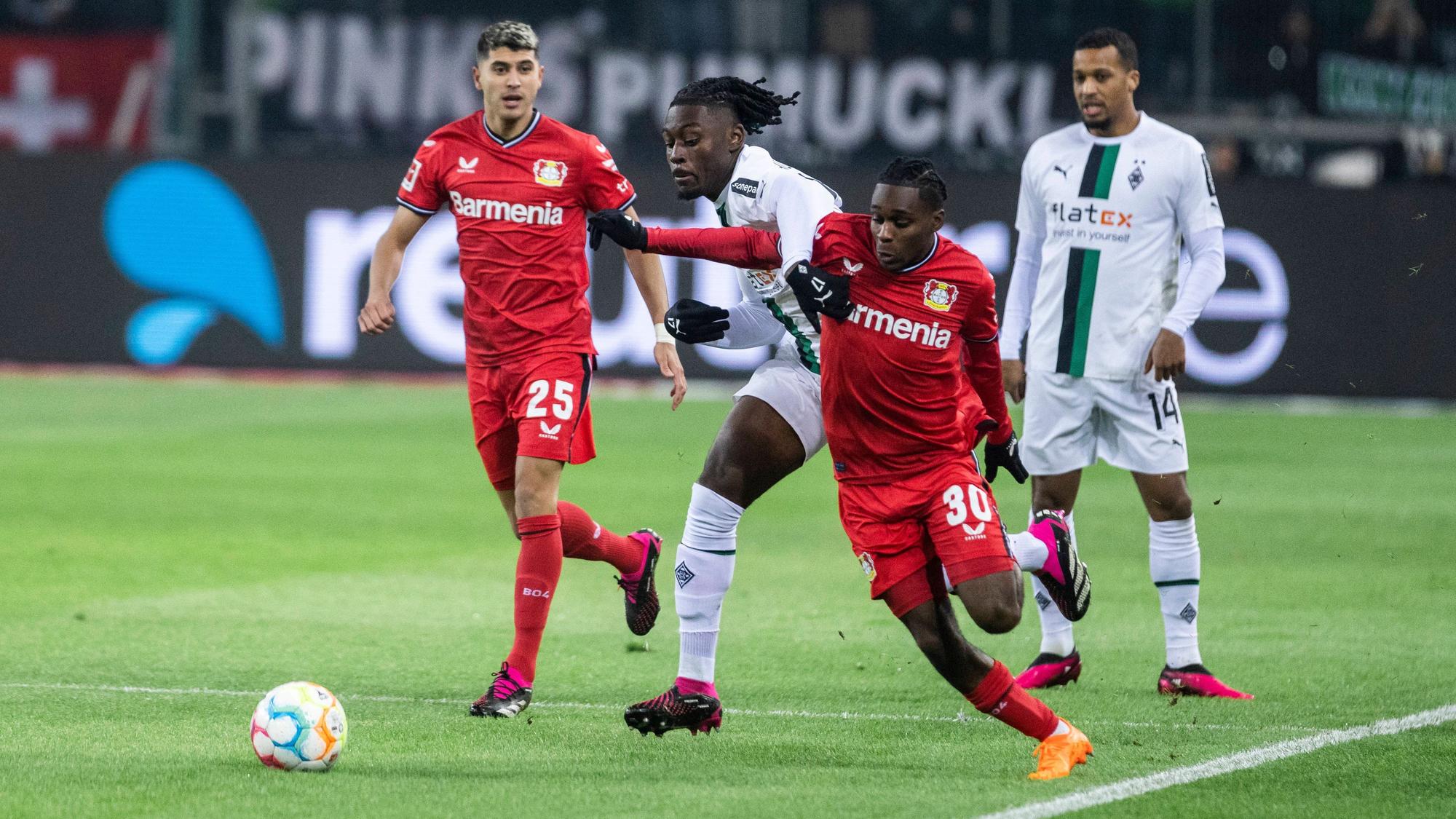 Gladbach-Profi Manu Koné (M.) hat gegen Jeremie Frimpong (r.) von Bayer Leverkusen große Mühe im Zweikampf. Das Foto stammt aus dem Hinspiel am 22. Januar 2023 im Borussia-Park. Koné verliert das Laufduell.