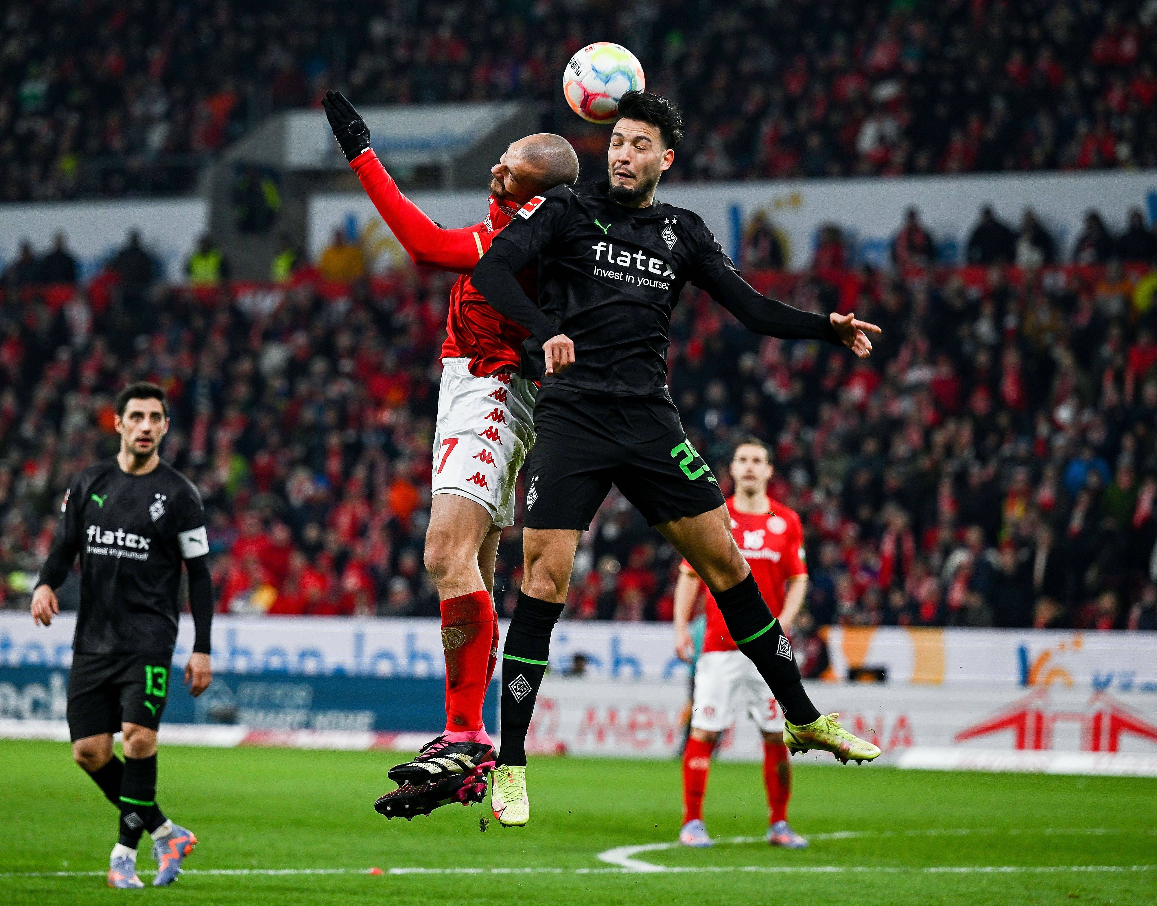 2Mainz-Stürmer Ludovic Ajorque (l.) am 24. Februar 2023 im Luftzweikampf mit Gladbach-Verteidiger Ramy Bensebaini (r.).