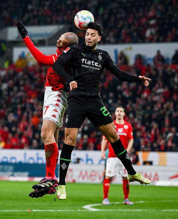 2Mainz-Stürmer Ludovic Ajorque (l.) am 24. Februar 2023 im Luftzweikampf mit Gladbach-Verteidiger Ramy Bensebaini (r.).
