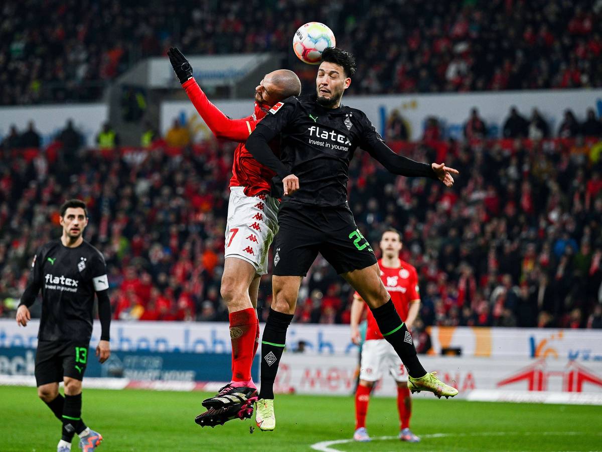 2Mainz-Stürmer Ludovic Ajorque (l.) am 24. Februar 2023 im Luftzweikampf mit Gladbach-Verteidiger Ramy Bensebaini (r.).