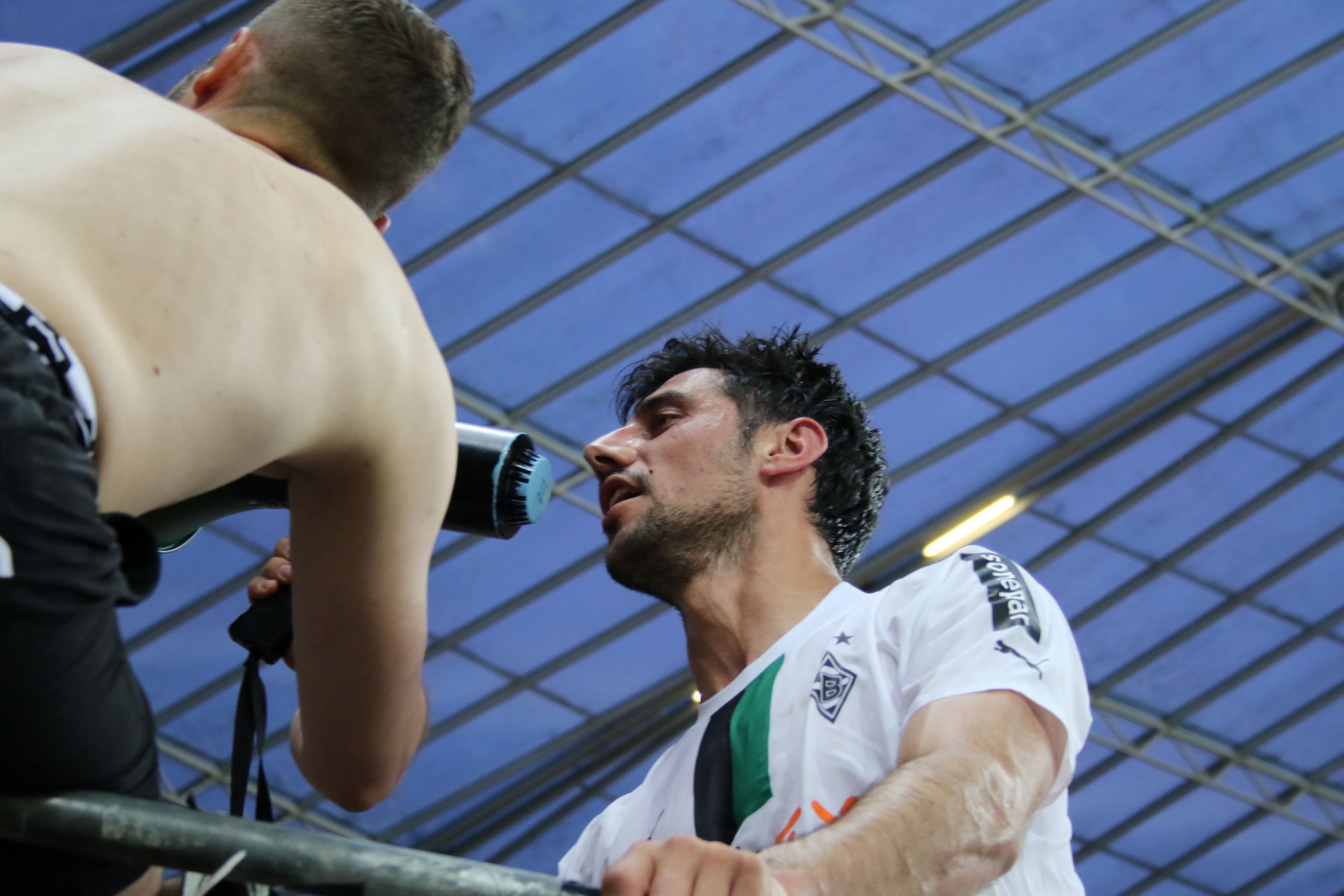 Gladbach-Capitano Lars Stindl ist nach dem 2:2-Remis bei Bayer Leverkusen (21. Mai 2023) von den Borussia-Fans gefeiert worden. Hier steht er auf dem Absperr-Zaun des Gästeblocks und spricht in ein Megafon der Anhänger. Zu sehen sind Stindl und ein Fan.