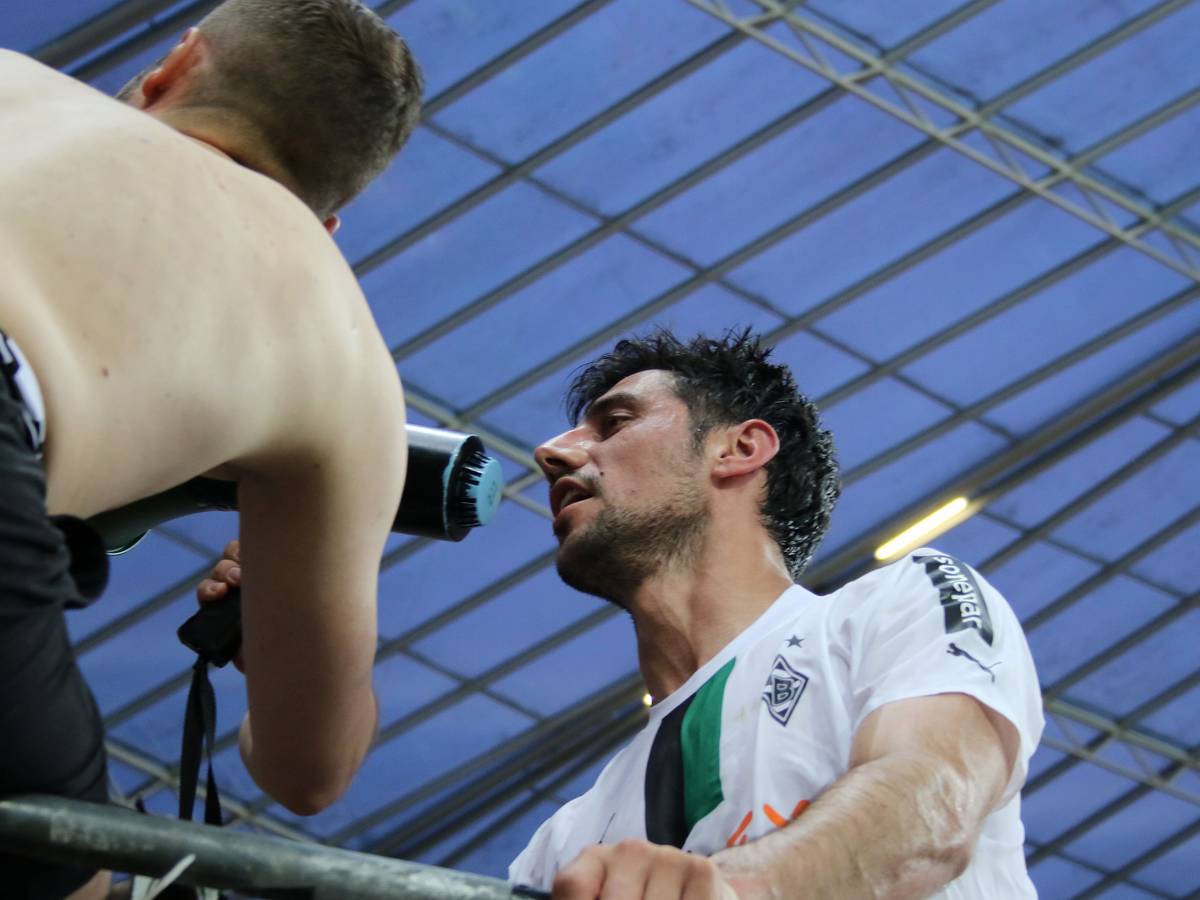 Gladbach-Capitano Lars Stindl ist nach dem 2:2-Remis bei Bayer Leverkusen (21. Mai 2023) von den Borussia-Fans gefeiert worden. Hier steht er auf dem Absperr-Zaun des Gästeblocks und spricht in ein Megafon der Anhänger. Zu sehen sind Stindl und ein Fan.