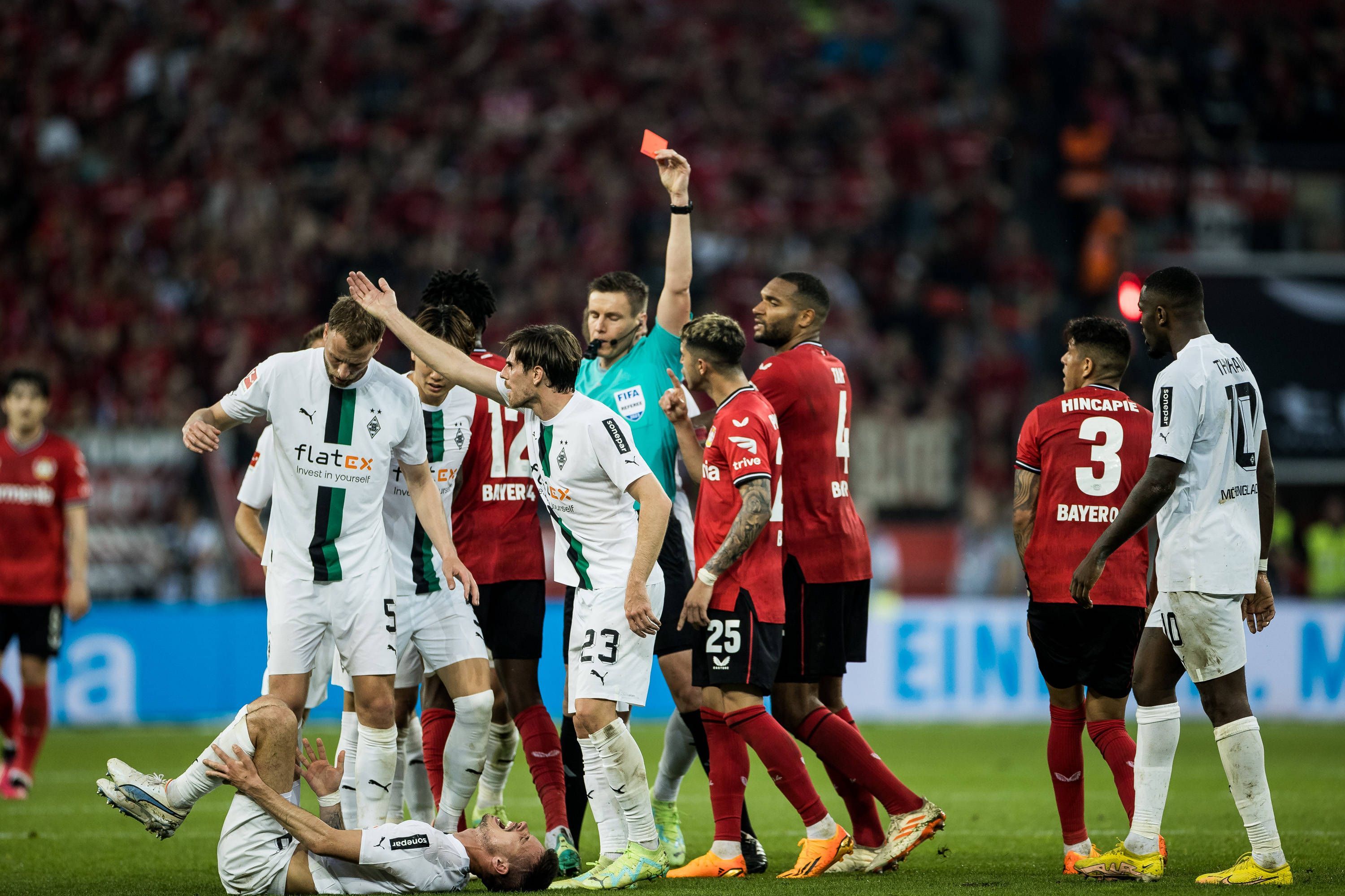 Gladbach-Star Julian Weigl liegt verletzt am Boden, Piero Hincapie von Bayer Leverkusen sieht nach seinem Foulspiel die Rote Karte (21. Mai 2023). Der Schiedsrichter hat den roten Karton in der Hand.