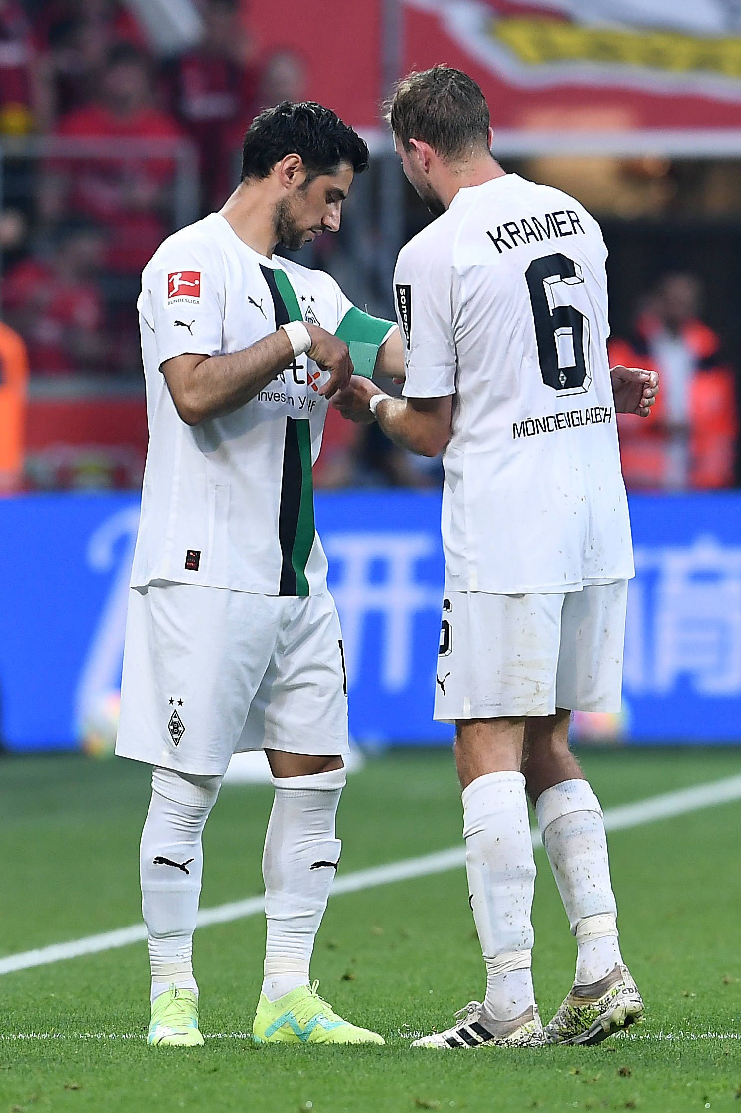 Christoph Kramer (r.) überreicht an Lars Stindl (l.) die Kapitänsbinde von Borussia Mönchengladbach. Das Foto zeigt die beiden am 21. Mai 2023 während des Bundesliga-Duells bei Bayer Leverkusen. Kramer macht die Binde an Stindls Arm fest.