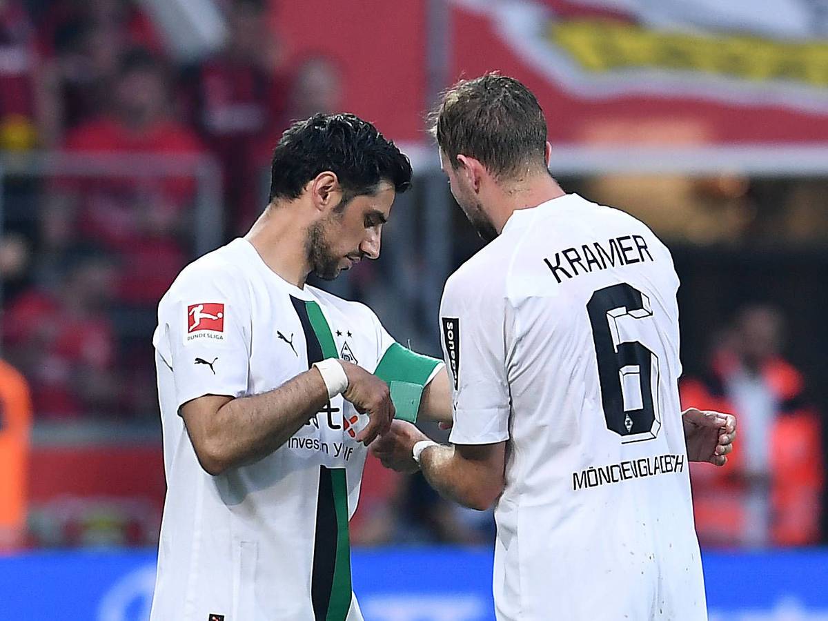 Christoph Kramer (r.) überreicht an Lars Stindl (l.) die Kapitänsbinde von Borussia Mönchengladbach. Das Foto zeigt die beiden am 21. Mai 2023 während des Bundesliga-Duells bei Bayer Leverkusen. Kramer macht die Binde an Stindls Arm fest.