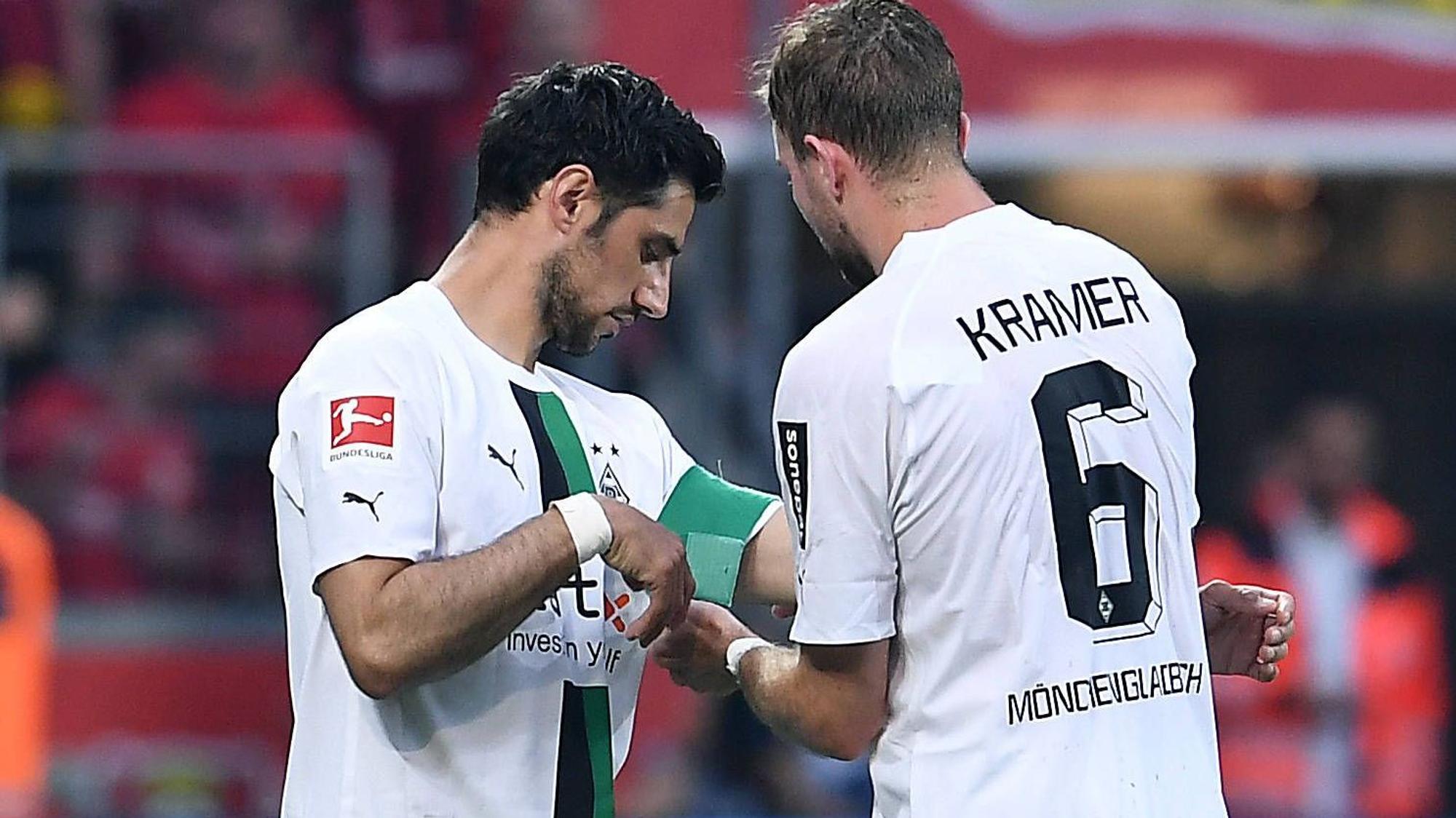 Christoph Kramer (r.) überreicht an Lars Stindl (l.) die Kapitänsbinde von Borussia Mönchengladbach. Das Foto zeigt die beiden am 21. Mai 2023 während des Bundesliga-Duells bei Bayer Leverkusen. Kramer macht die Binde an Stindls Arm fest.