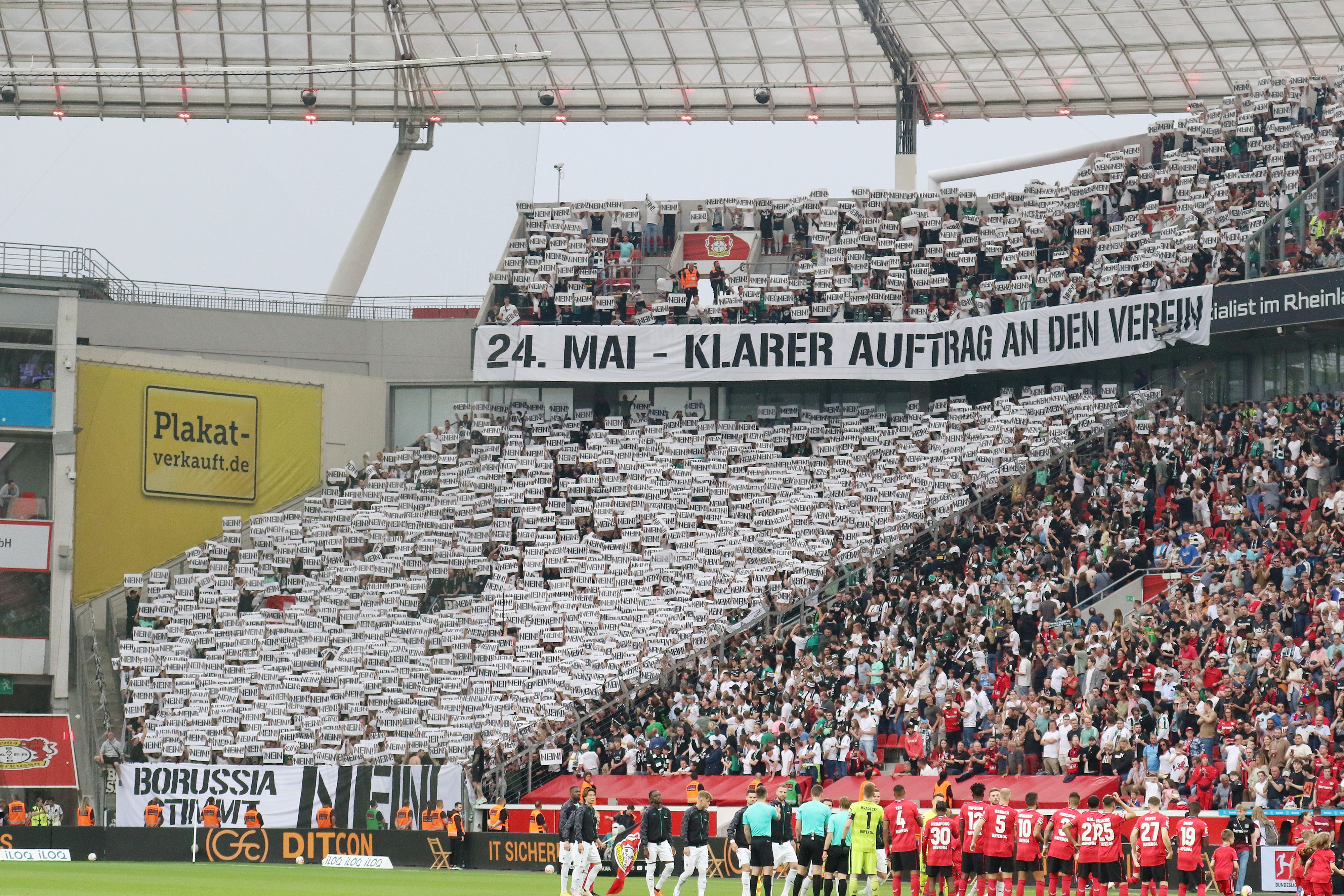 Die Fans von Borussia Mönchengladbach fordern ihren Klub vor dem Bundesliga-Auswärtsspiel bei Bayer Leverkusen (21. Mai 2023) auf, gegen den geplanten DFL-Anteilsverkauf zu stimmen. Auf Bannern steht „24. Mai – klarer Auftrag an den Verein“ und „Borussia stimmt Nein!“. Die Fans halten zahlreiche Schilder mit dem Wort „Nein“ hoch.