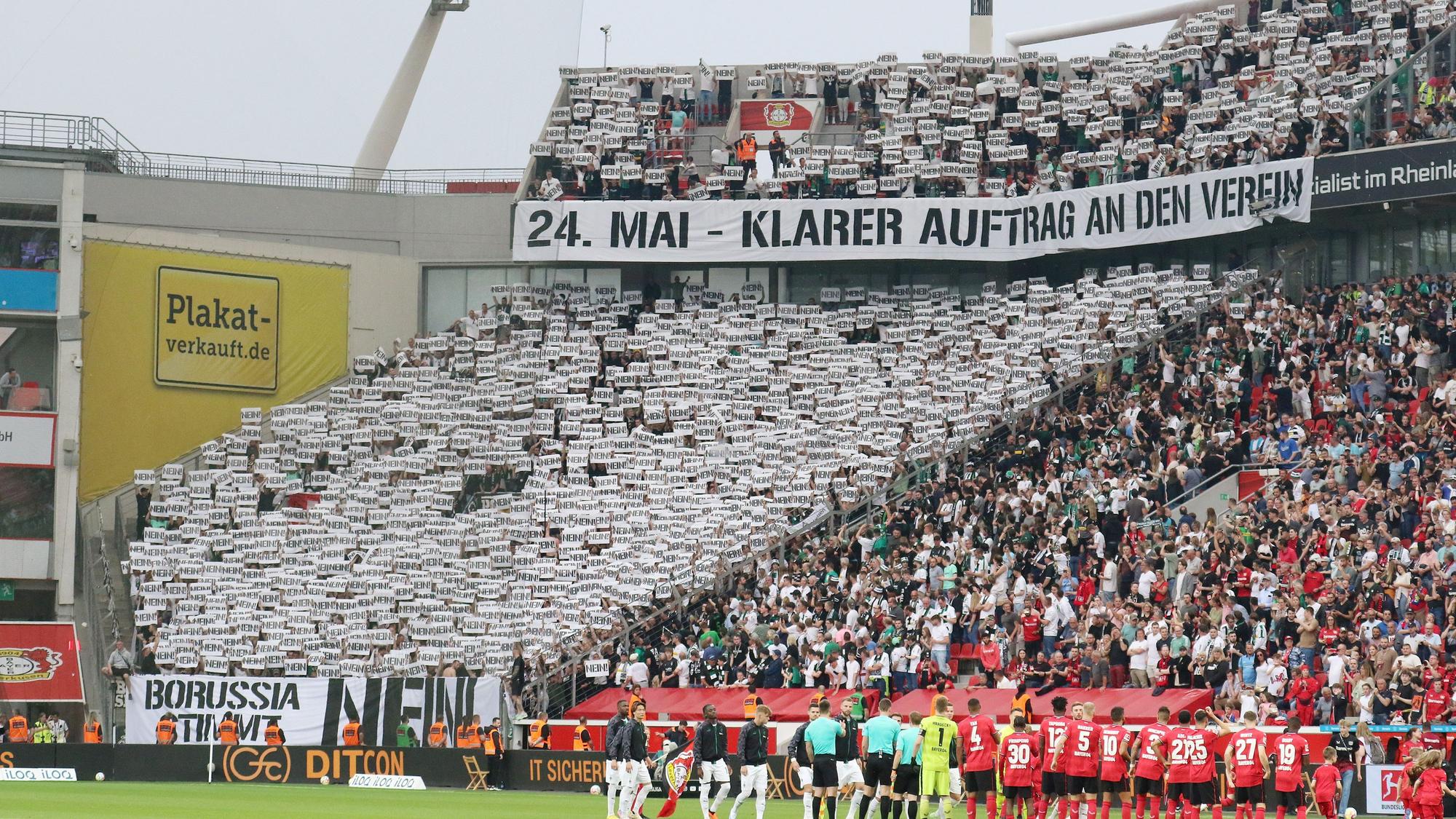 Die Fans von Borussia Mönchengladbach fordern ihren Klub vor dem Bundesliga-Auswärtsspiel bei Bayer Leverkusen (21. Mai 2023) auf, gegen den geplanten DFL-Anteilsverkauf zu stimmen. Auf Bannern steht „24. Mai – klarer Auftrag an den Verein“ und „Borussia stimmt Nein!“. Die Fans halten zahlreiche Schilder mit dem Wort „Nein“ hoch.