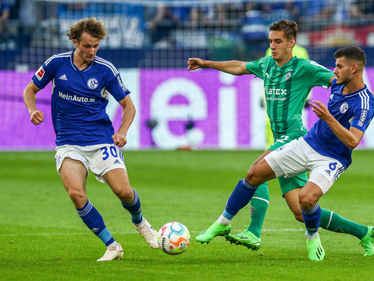 Alex Kral (l.) vom FC Schalke 04 am 13. August 2023 im Zweikampf mit Florian Neuhaus von Borussia Mönchengladbach. Daneben der Schalker Tom Krauß.