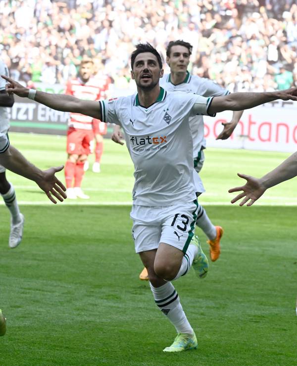 Luca Netz (r.) und Lars Stindl jubeln über einen Treffer von Borussia Mönchengladbach im Bundesliga-Finish (27. Mai 2023) gegen den FC Augsburg im Borussia-Park. Sie breiten die Arme zum Jubel aus.
