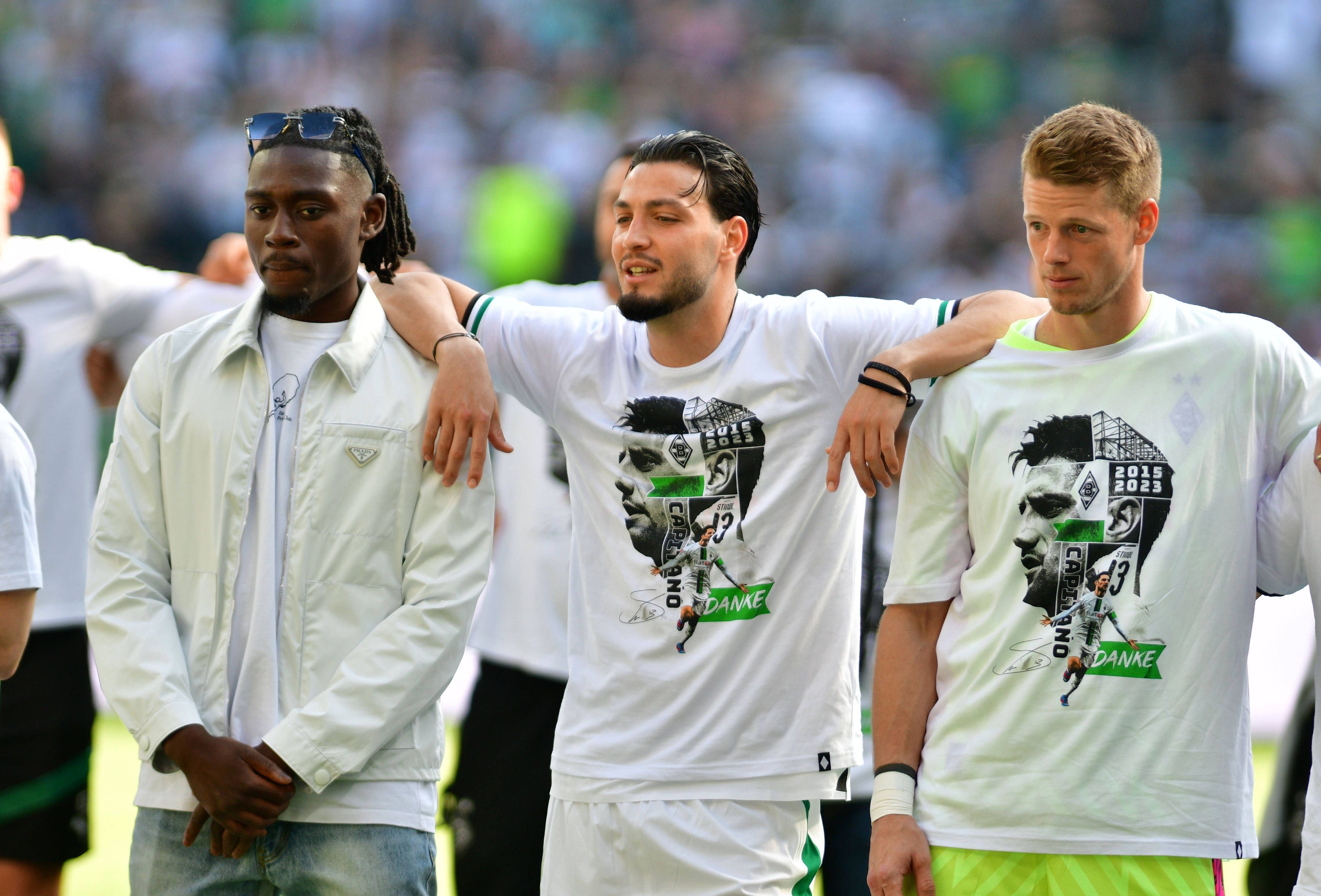 Die Gladbach-Spieler Ramy Bensebaini (M.), Manu Koné (l.) und Jonas Omlin (r.) im Borussia-Park, hier zu sehen bei der Verabschiedung von den Fohlen-Fans nach dem Bundesliga-Finale (27. Mai 2023) gegen den FC Augsburg. Die Spieler haben sich teilweise umarmt und schauen Richtung Nordkurve.