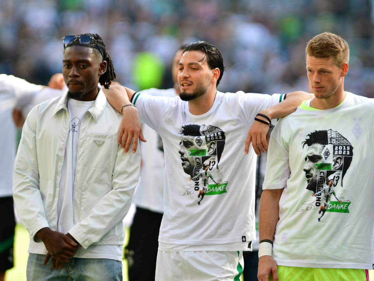 Die Gladbach-Spieler Ramy Bensebaini (M.), Manu Koné (l.) und Jonas Omlin (r.) im Borussia-Park, hier zu sehen bei der Verabschiedung von den Fohlen-Fans nach dem Bundesliga-Finale (27. Mai 2023) gegen den FC Augsburg. Die Spieler haben sich teilweise umarmt und schauen Richtung Nordkurve.