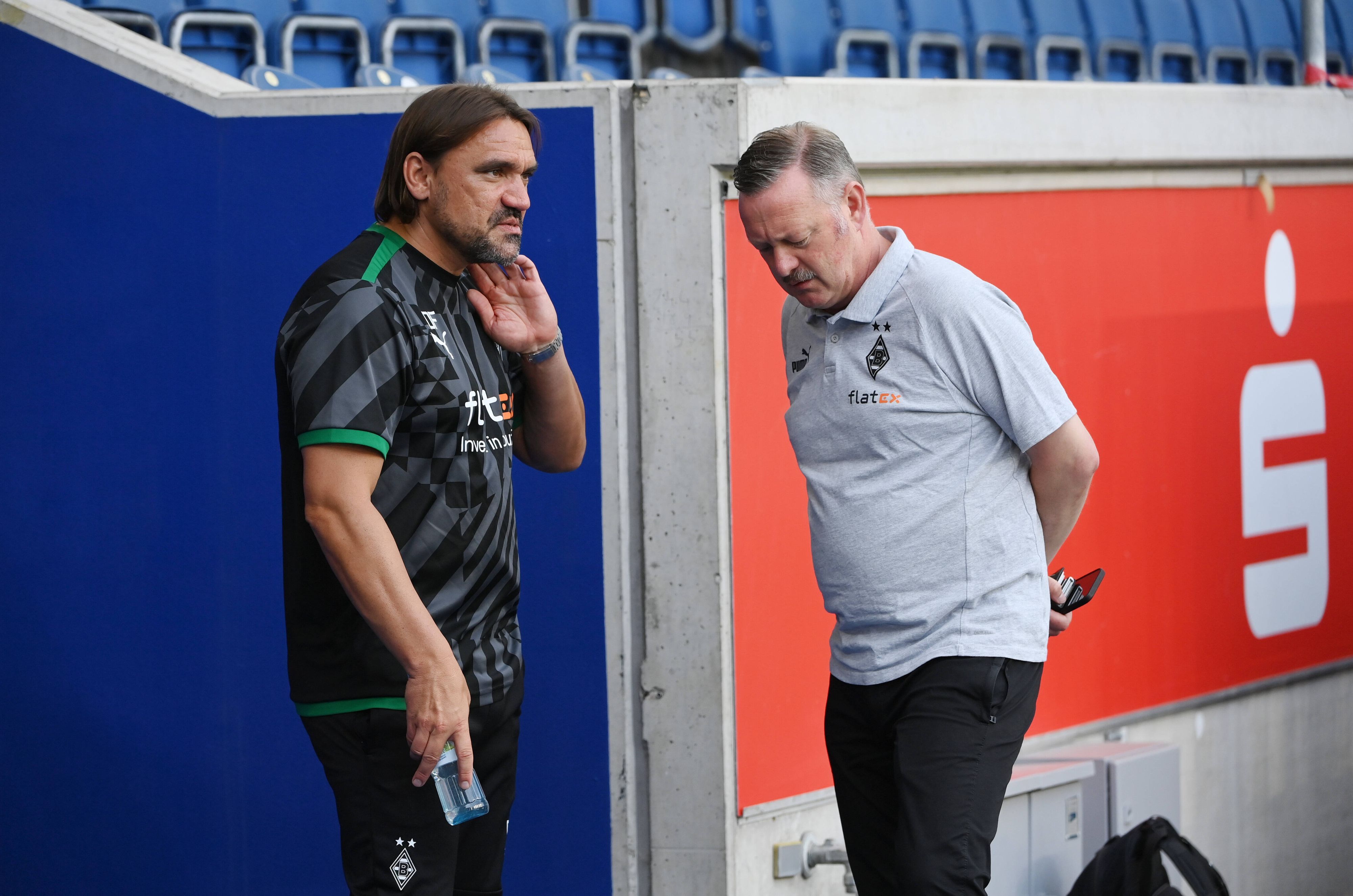 Gladbach-Trainer Daniel Farke (l.) im Gespräch mit Borussia-Manager Roland Virkus. Das Foto zeigt die beiden am 17. Juli 2022 in Duisburg. Farke hat eine Trinkflasche in der rechten Hand.