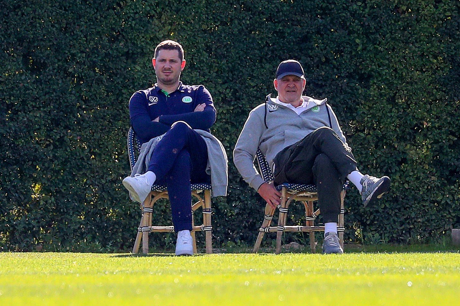 Nils Schmadtke (l.), hier zu sehen neben seinem Vater Jörg Schmadtke, als beide noch für Fußball-Bundesligist VfL Wolfsburg gearbeitet haben. Das Foto stammt vom 6. Januar 2023 und wurde während eines Trainingslagers in Portugal gemacht. Die beiden sitzen jeweils auf einem Stuhl.