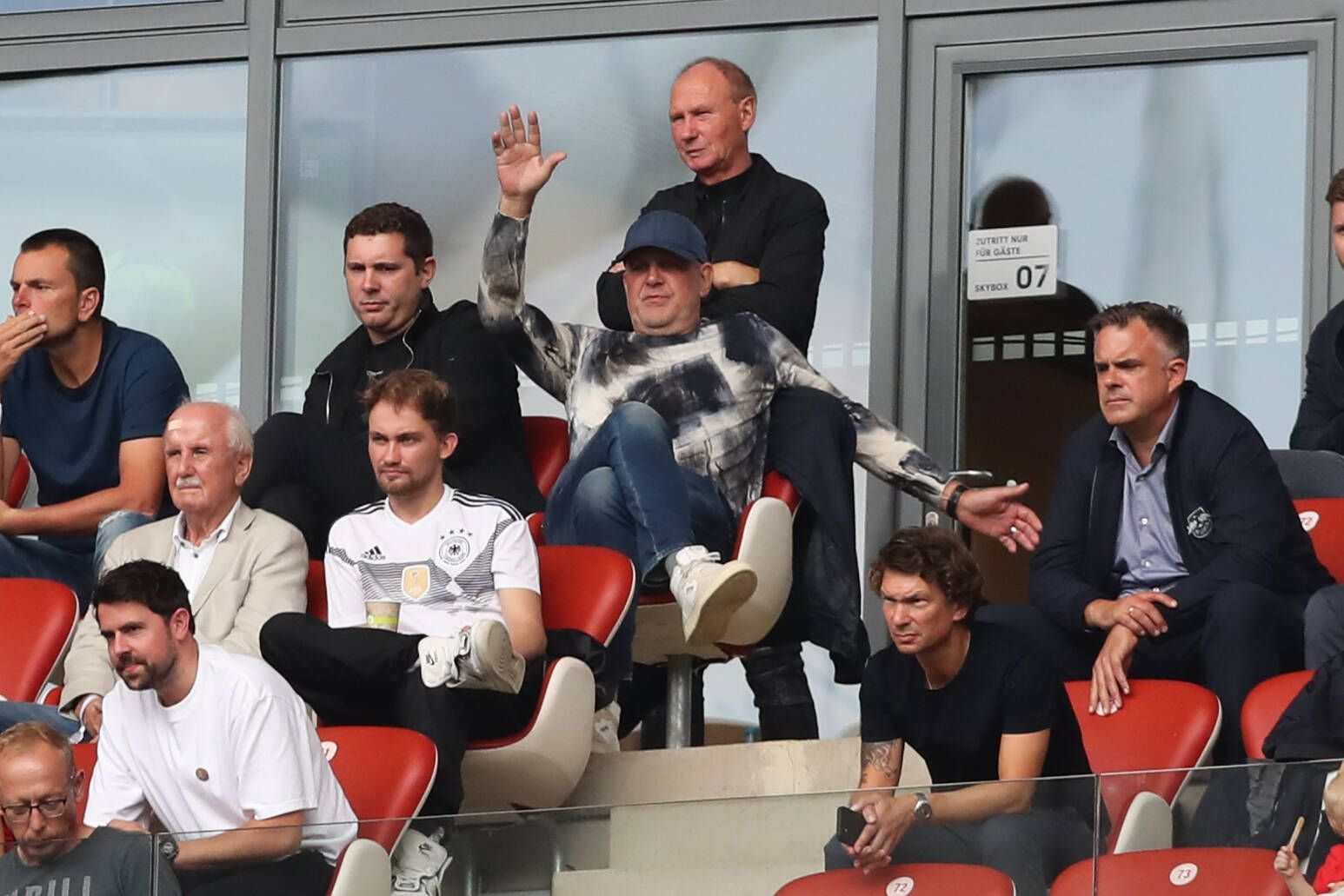 Nils Schmadtke (ober Reihe, links) sitzt neben seinem Vater Jörg Schmadtke, der inzwischen für den FC Liverpool arbeitet. Die beiden sind hier am 27. August 2022 in Leipzig zu sehen. Jörg Schmadtke macht Bewegungen mit den Armen.