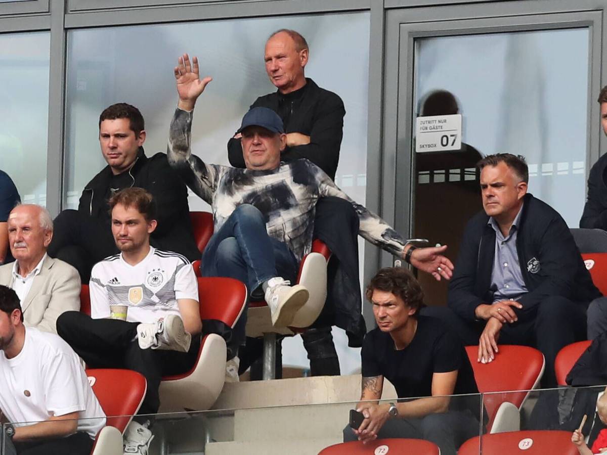 Nils Schmadtke (ober Reihe, links) sitzt neben seinem Vater Jörg Schmadtke, der inzwischen für den FC Liverpool arbeitet. Die beiden sind hier am 27. August 2022 in Leipzig zu sehen. Jörg Schmadtke macht Bewegungen mit den Armen.