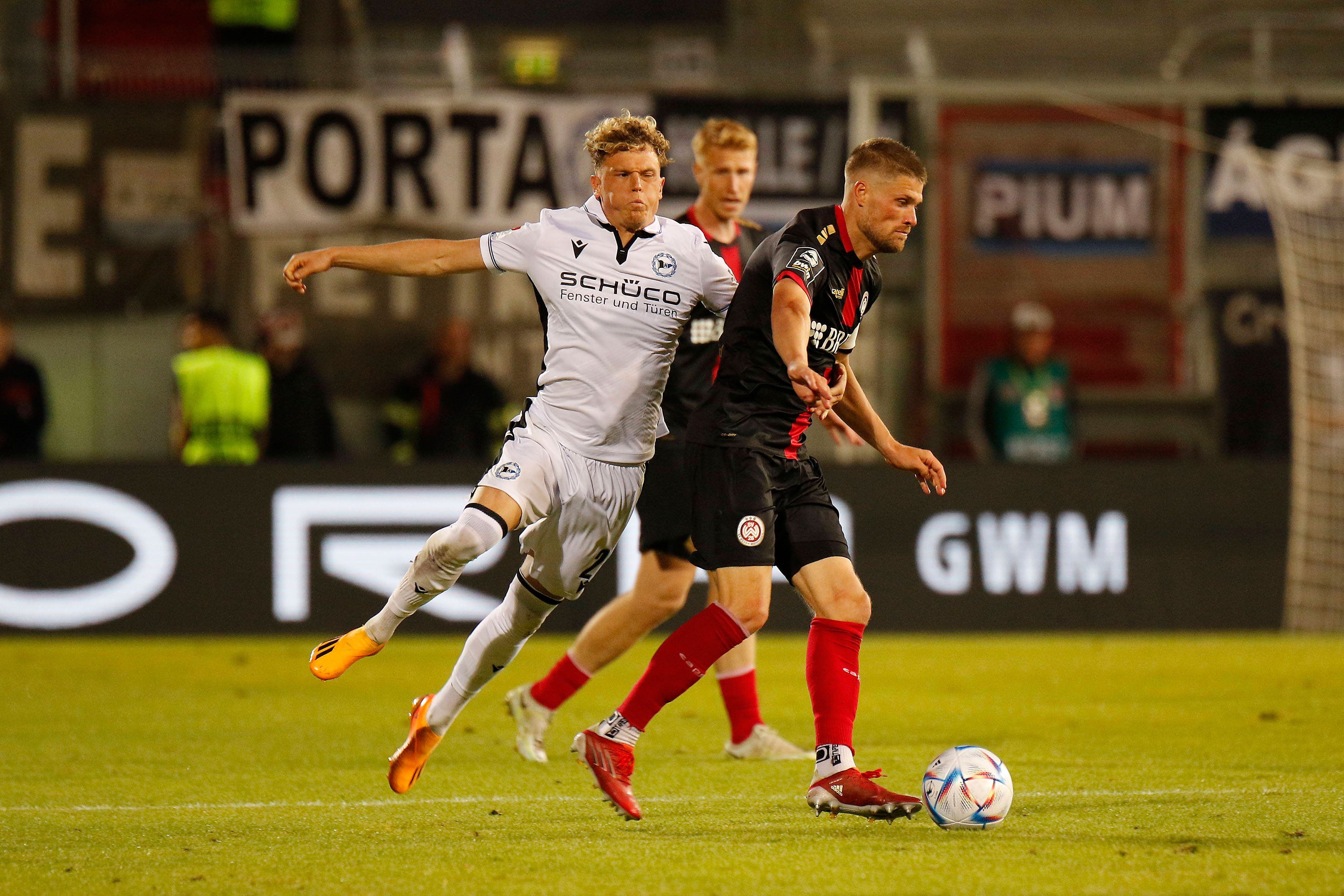 Kommt er bald zu Fußball-Bundesligist Borussia Mönchengladbach? Robin Hack (l.) von Arminia Bielefeld, hier zu sehen am 2. Juni 2023 im Relegations-Duell gegen Wehen Wiesbaden. Hack pustet im Zweikampf die Wangen auf.
