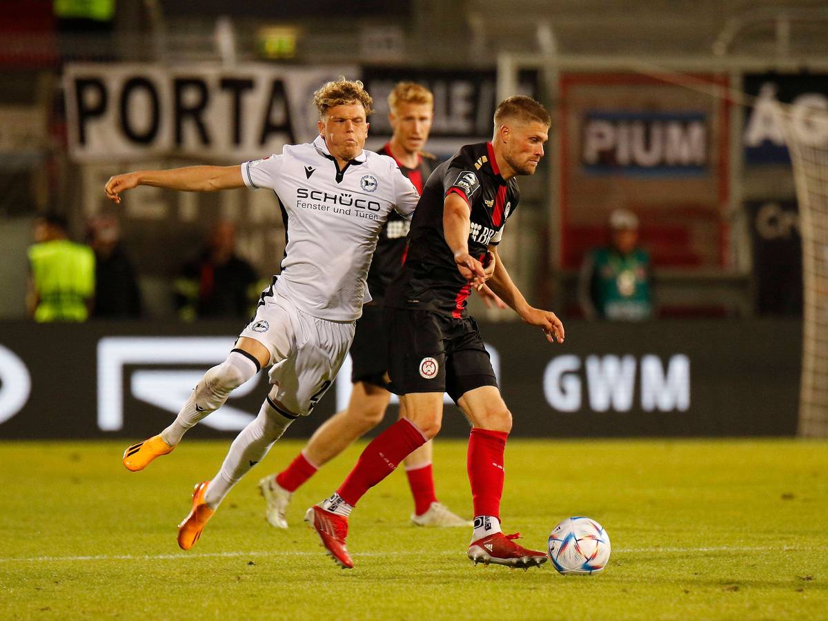 Kommt er bald zu Fußball-Bundesligist Borussia Mönchengladbach? Robin Hack (l.) von Arminia Bielefeld, hier zu sehen am 2. Juni 2023 im Relegations-Duell gegen Wehen Wiesbaden. Hack pustet im Zweikampf die Wangen auf.
