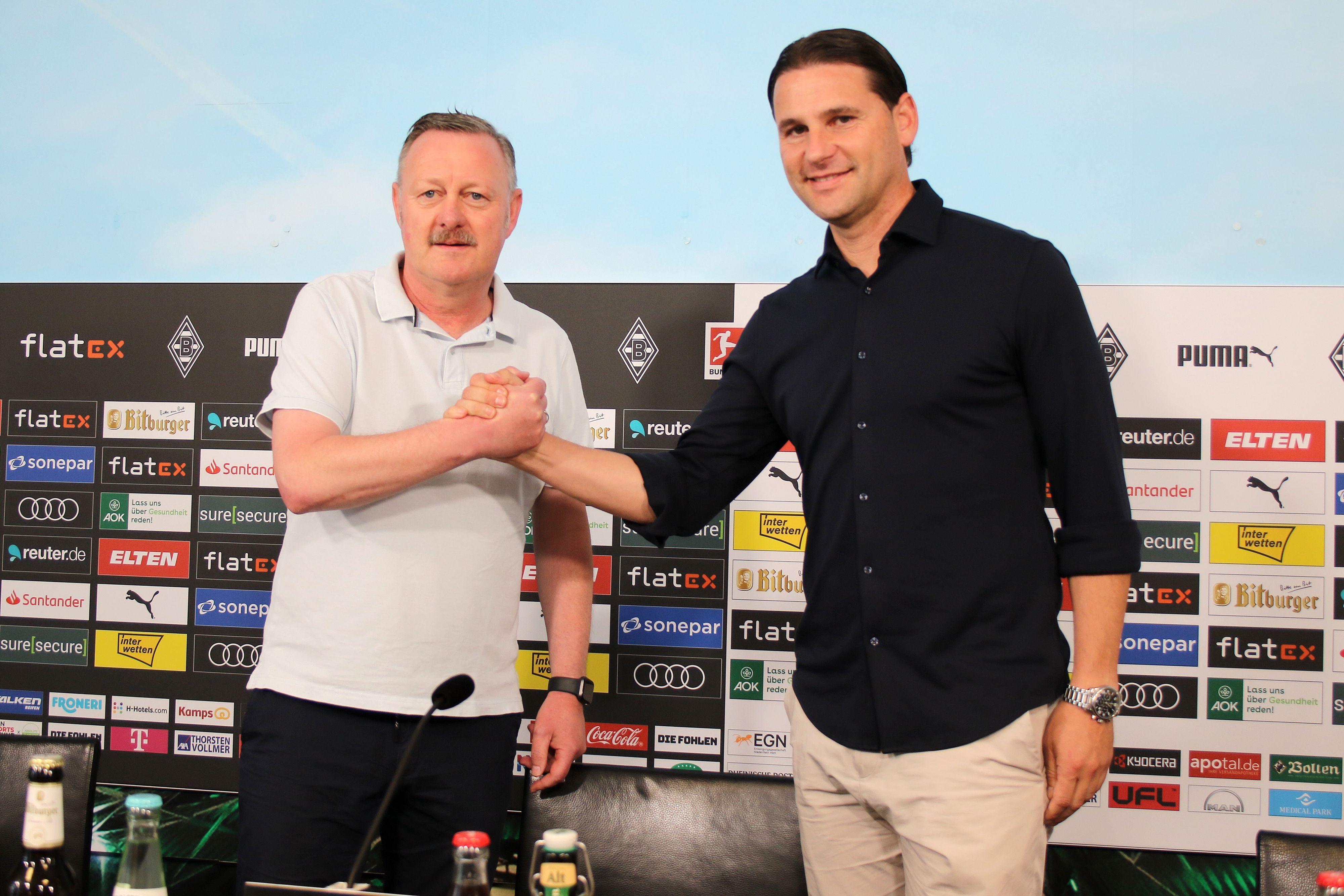 Der neue Gladbach-Trainer Gerardo Seoane (r.) und Borussia-Manager Roland Virkus (l.), hier zu sehen bei einer Pressekonferenz im Borussia-Park am 9. Juni 2023. Beide klatschen sich ab und lächeln Richtung Fotografen.