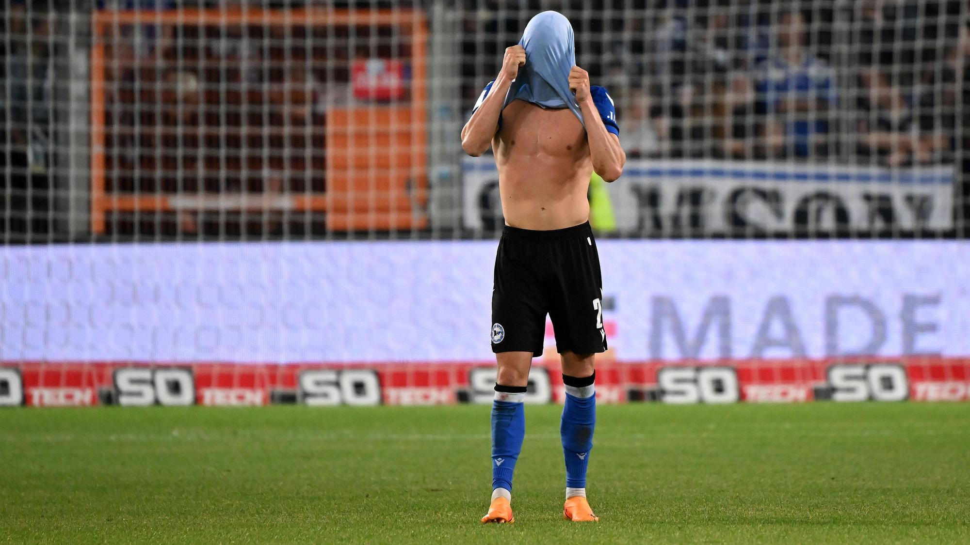 Aus Frust zieht sich Robin Hack nach dem Relegationsspiel von Arminia Bielefeld gegen den SV Wehen-Wiesbaden am 6. Juni 2023 das Trikot über den Kopf.